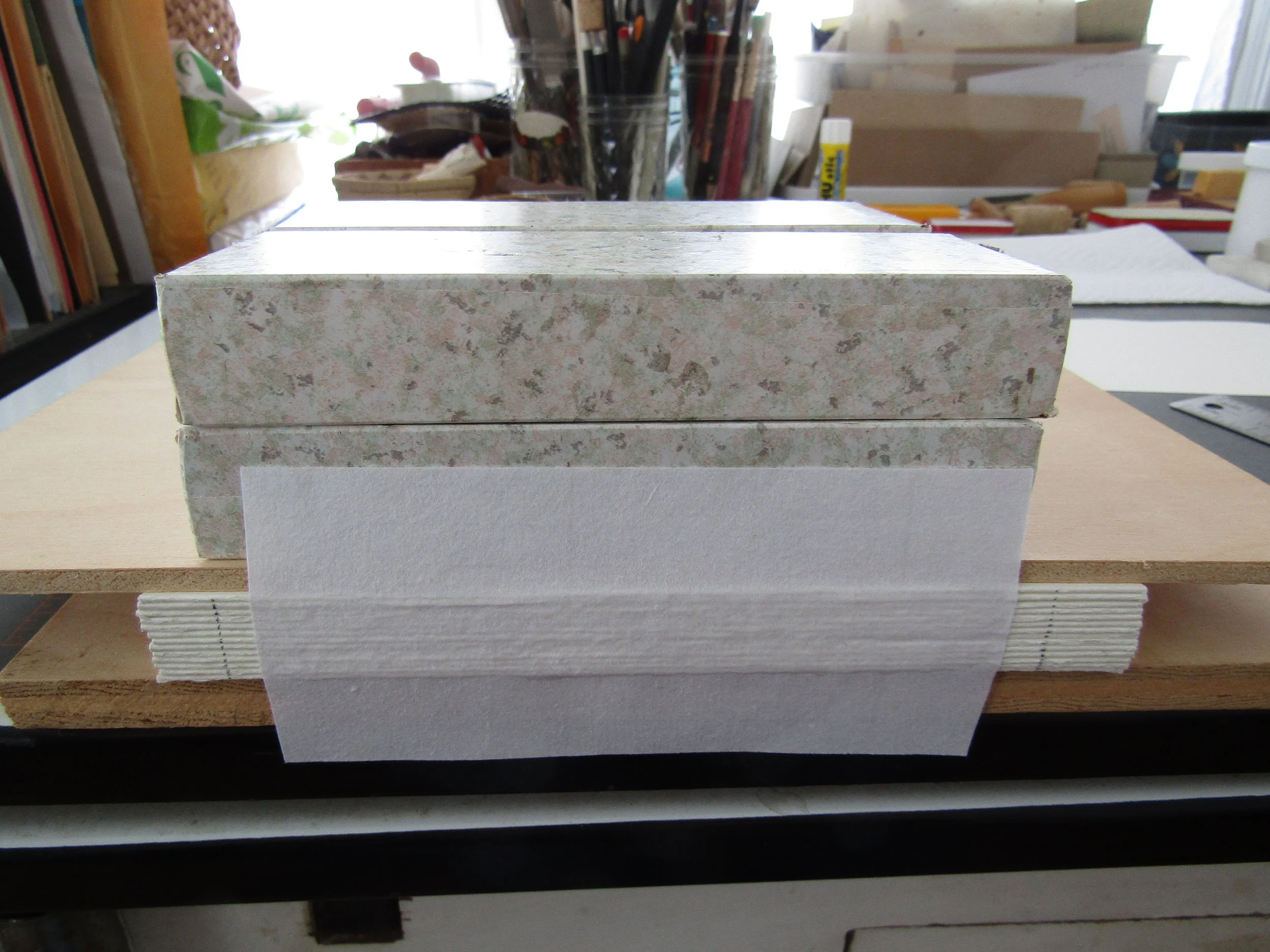 The pages are folded and weighted. A piece of Japanese paper is adhered to the spine. This will be hidden when the cover boards and outer spine are added. 