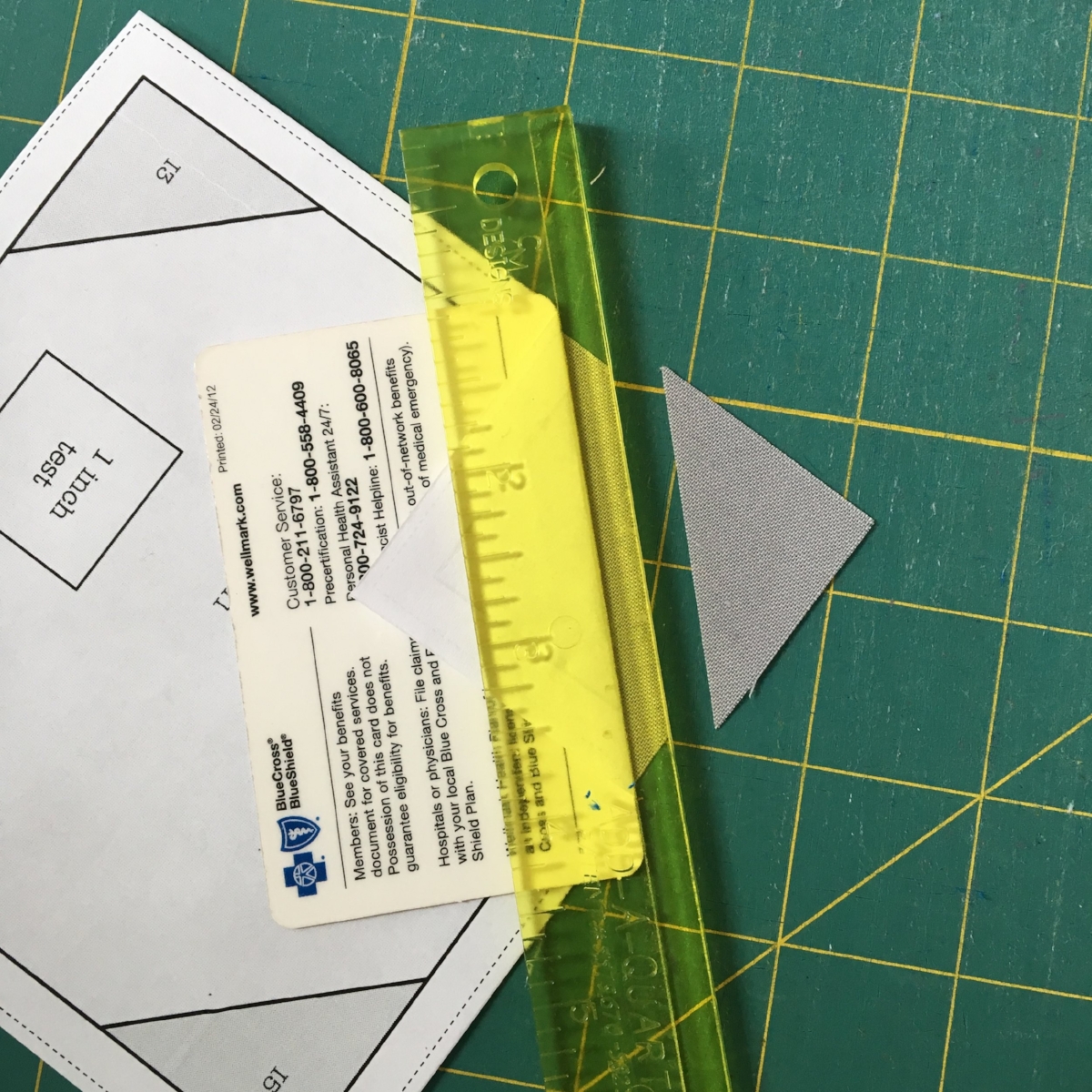 I used a dab of fabric glue to secure the 5" center square positioned in the center of the template, covering the seam allowances on all sides (it's tight so if you're slightly short, don't worry, it's going to be fiiiiiiine). Place your folding aid (an expired insurance card here) along one seaming line, fold the paper back , align the Add-A-Quarter ruler and trim before adding your triangle accent pieces (in Chartreuse for my block) . It makes the alignment of the triangles a bit easier.