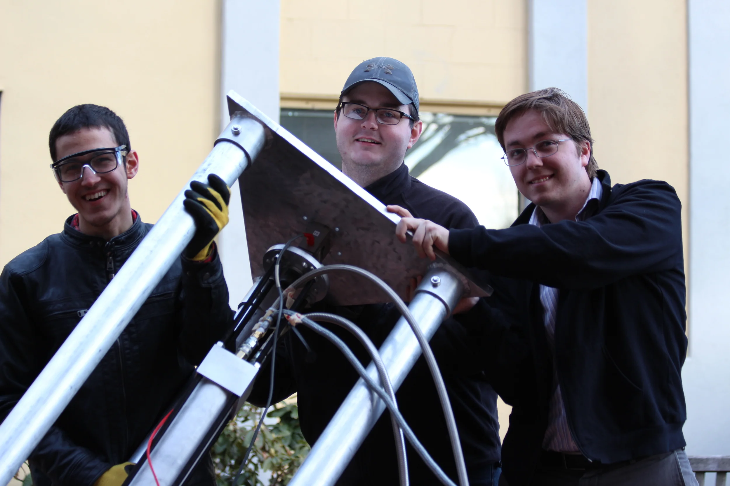  (From left to right) Mehmet Akbulut, Drew Kelly and Tom Halstead lifting the Mk III hybrid motor in the test stand 