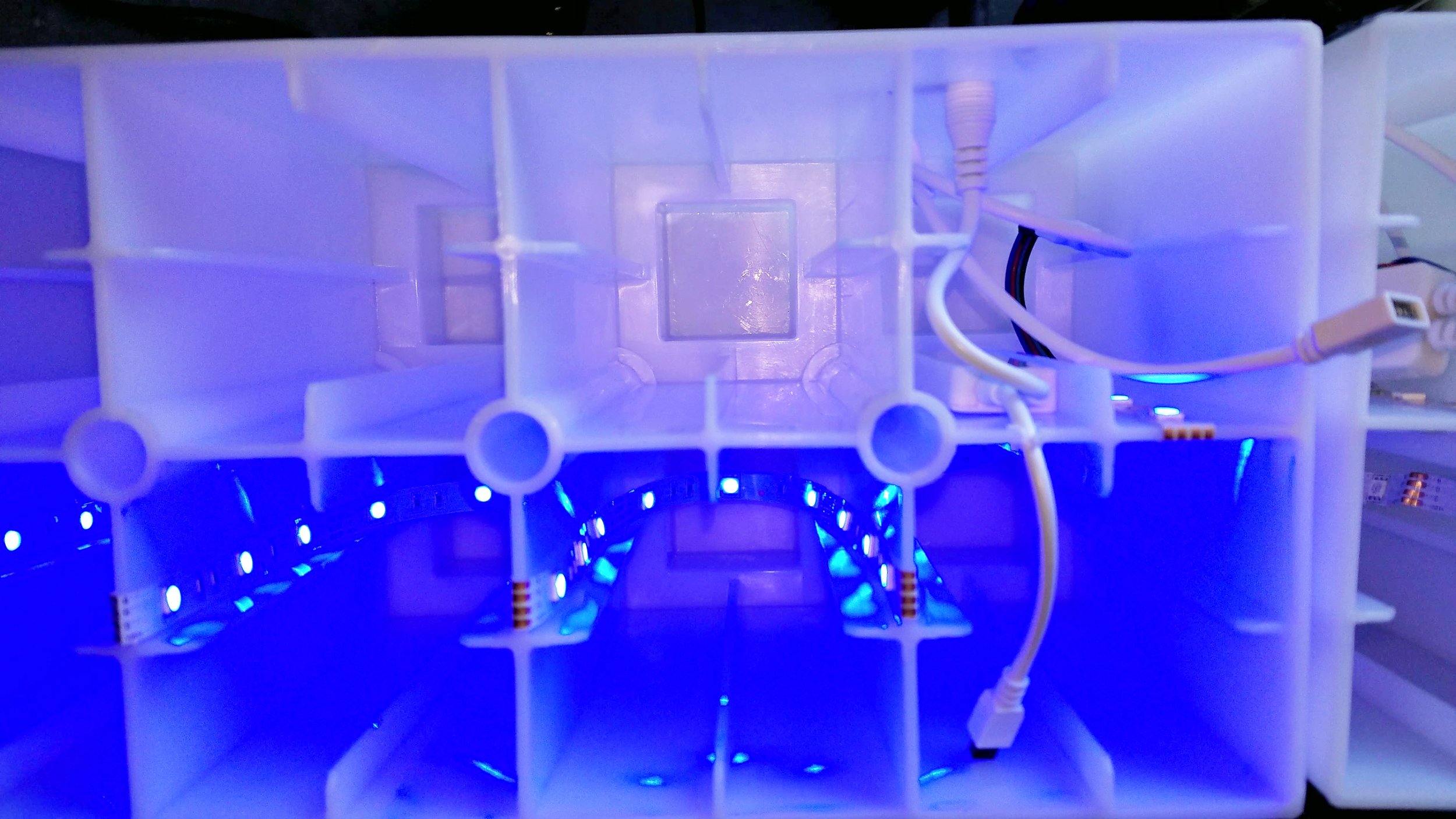 Underside of a translucent block showing LED strip lights and one of the two controller modules