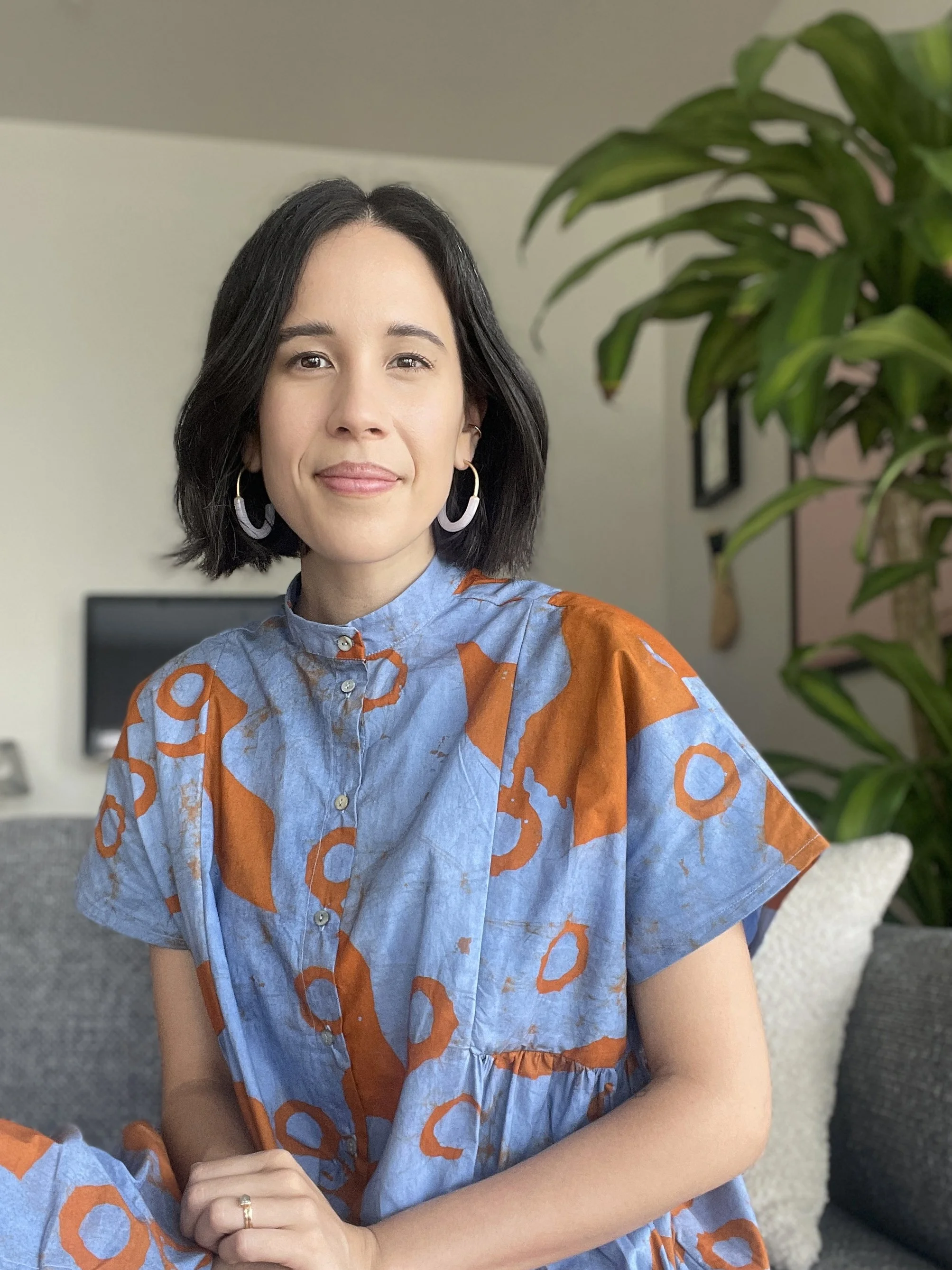 A headshot of Katie Lim in her home wearing a handmade textile dress.