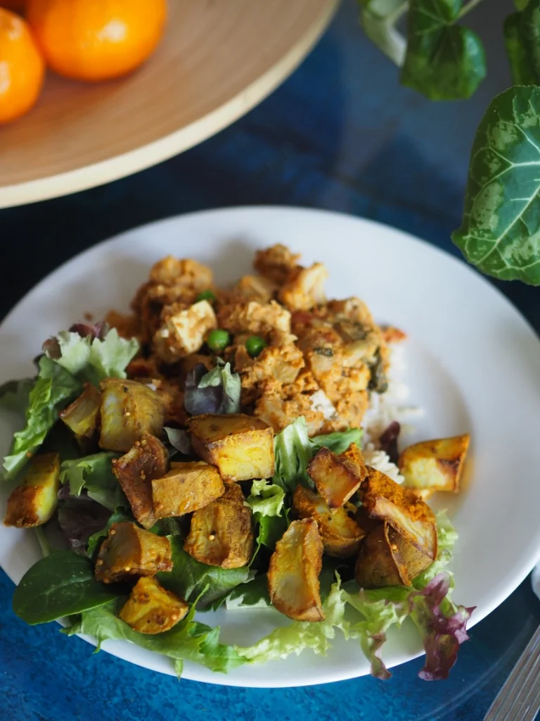 An easy recipe, spiced Indian roast potatoes are the perfect textural contrast with creamy cauliflower curry. All vegan, all delicious. 