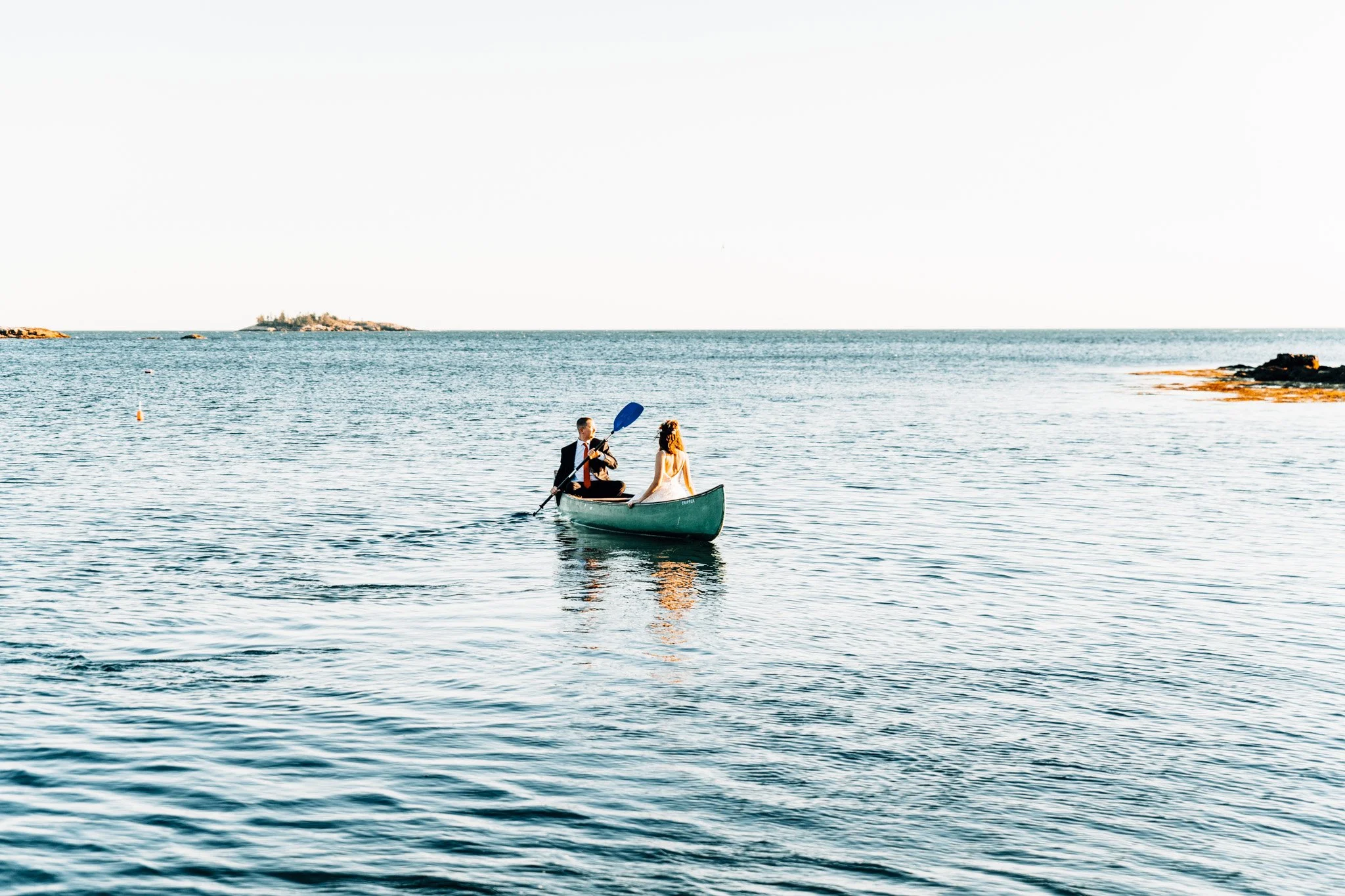Wide view of Alette and Kieron canoeing on open water off Pratts Island near Boothbay Harbor, Maine