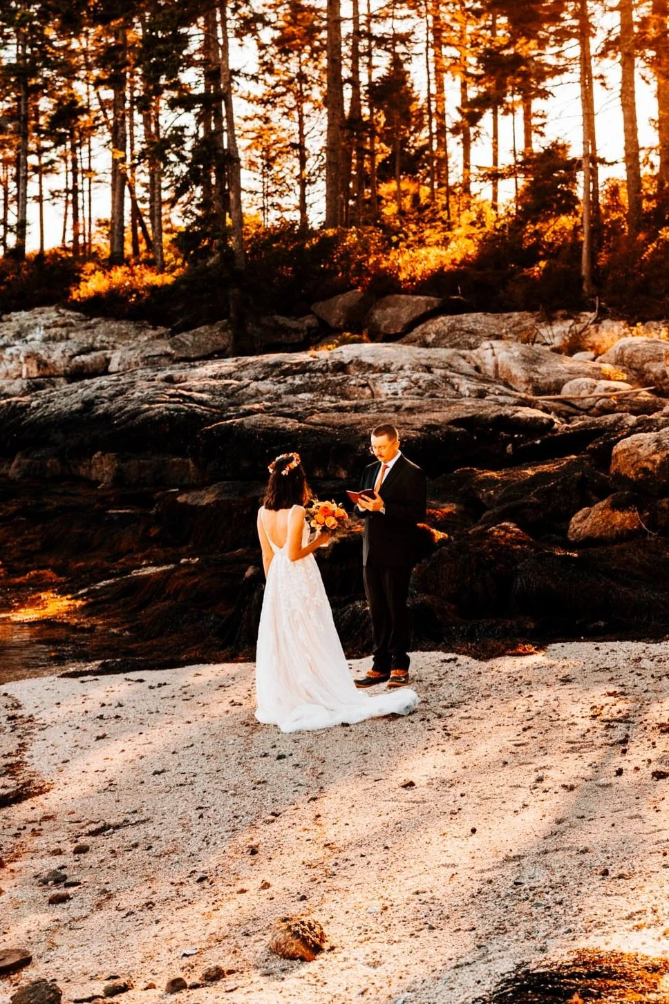 Kieron reading his private vows to Alette on a secluded pebble beach near Boothbay Harbor, golden light through the spruce