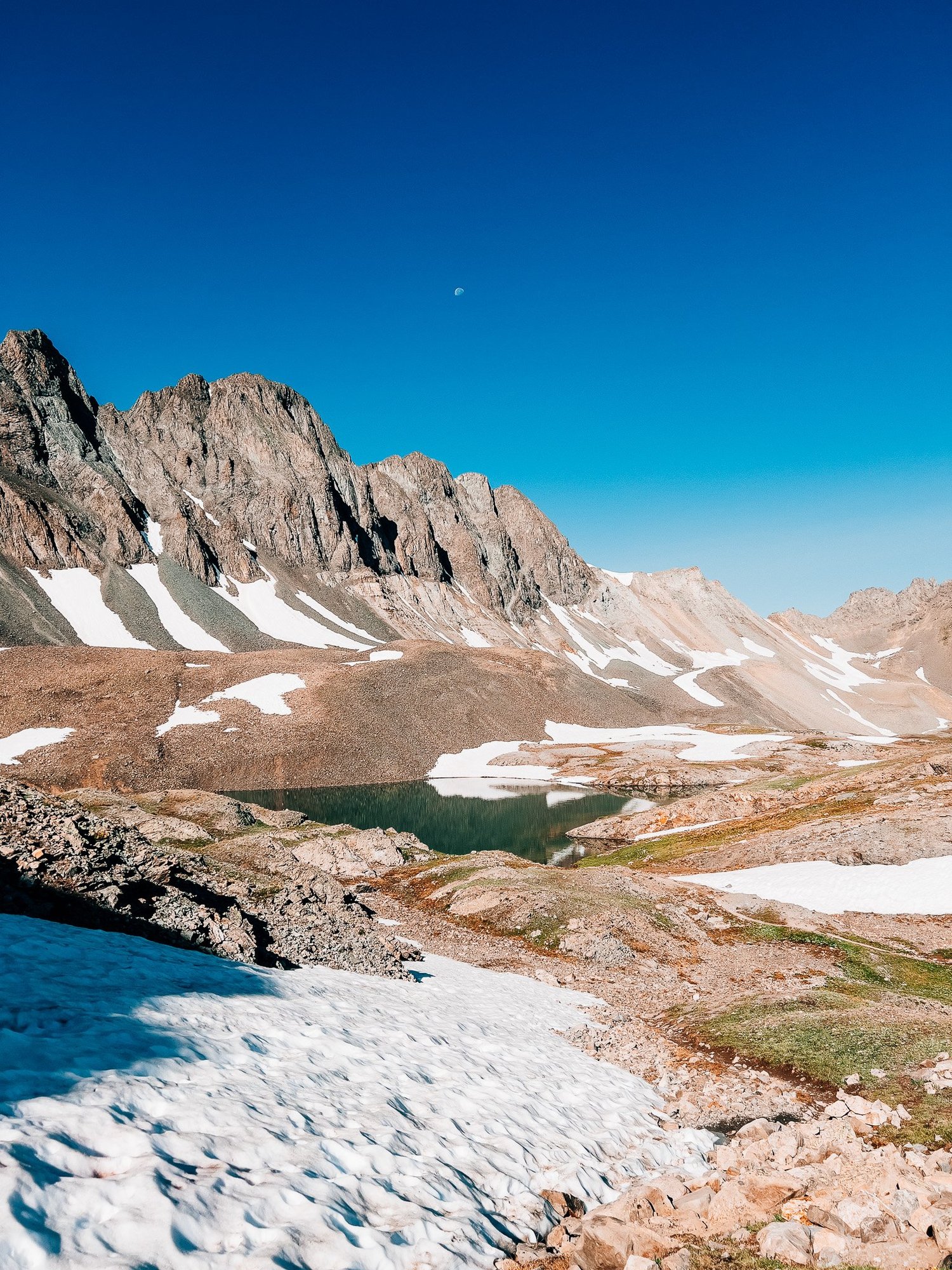 The turquoise alpine lake below the trail