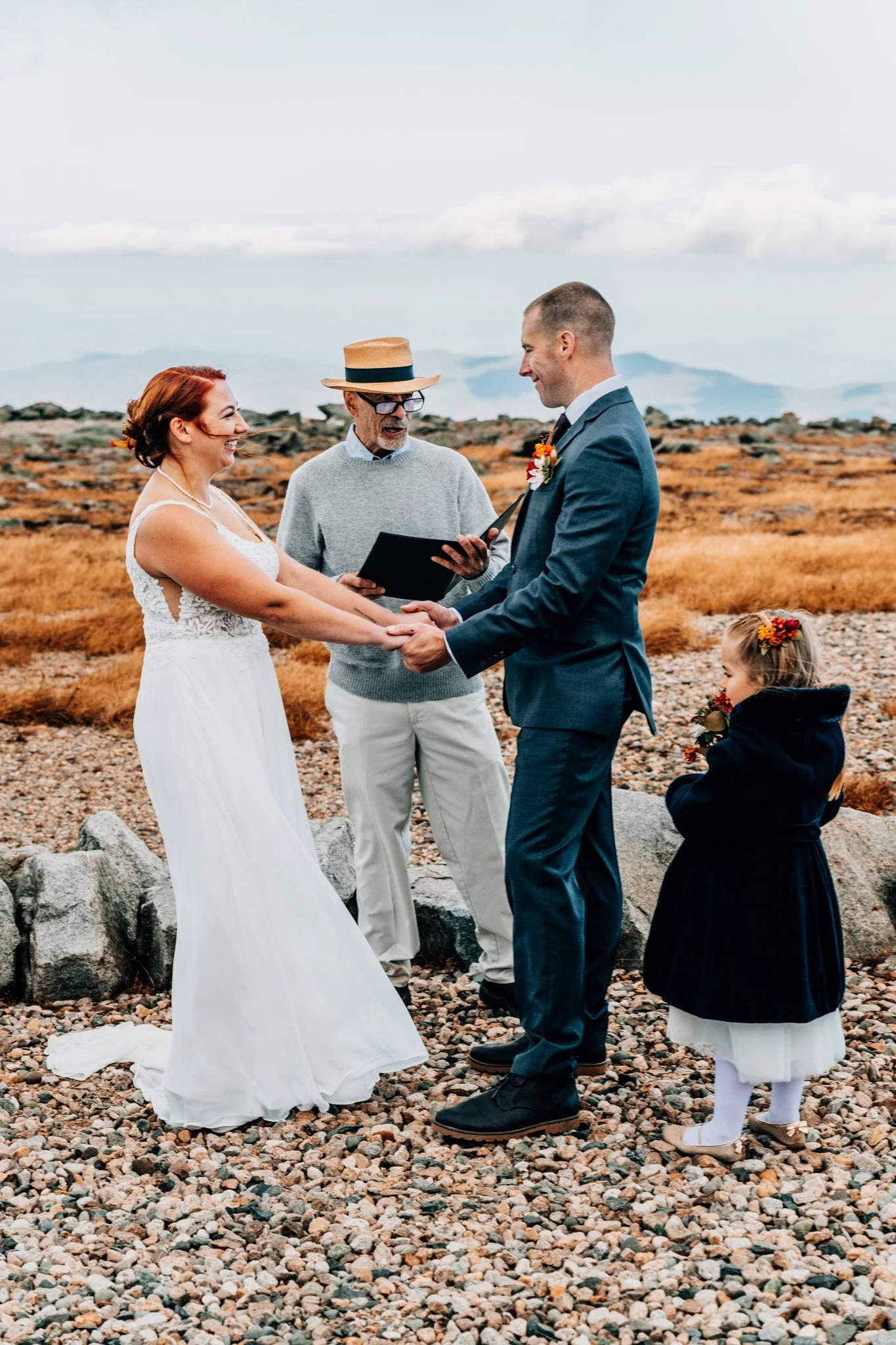 Danielle and Tom holding hands during their vows on Mount Washington, with their officiant and flower girl beside them