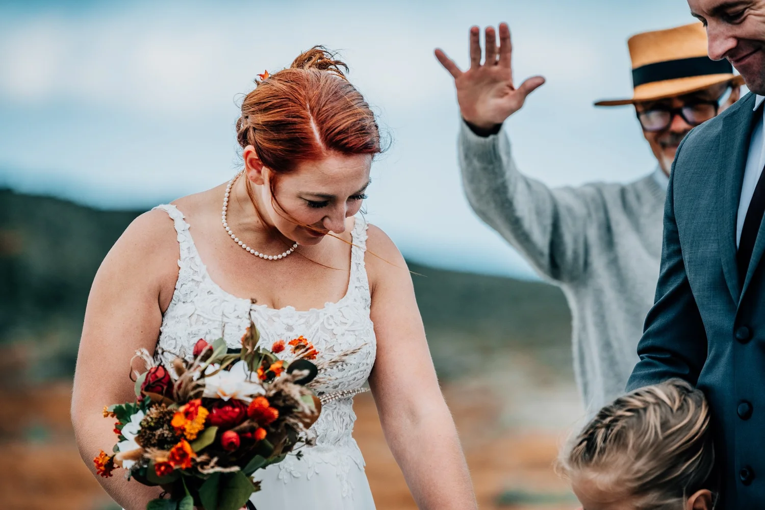 Bride laughing during the blessing at her Mount Washington elopement ceremony, officiant's hand raised