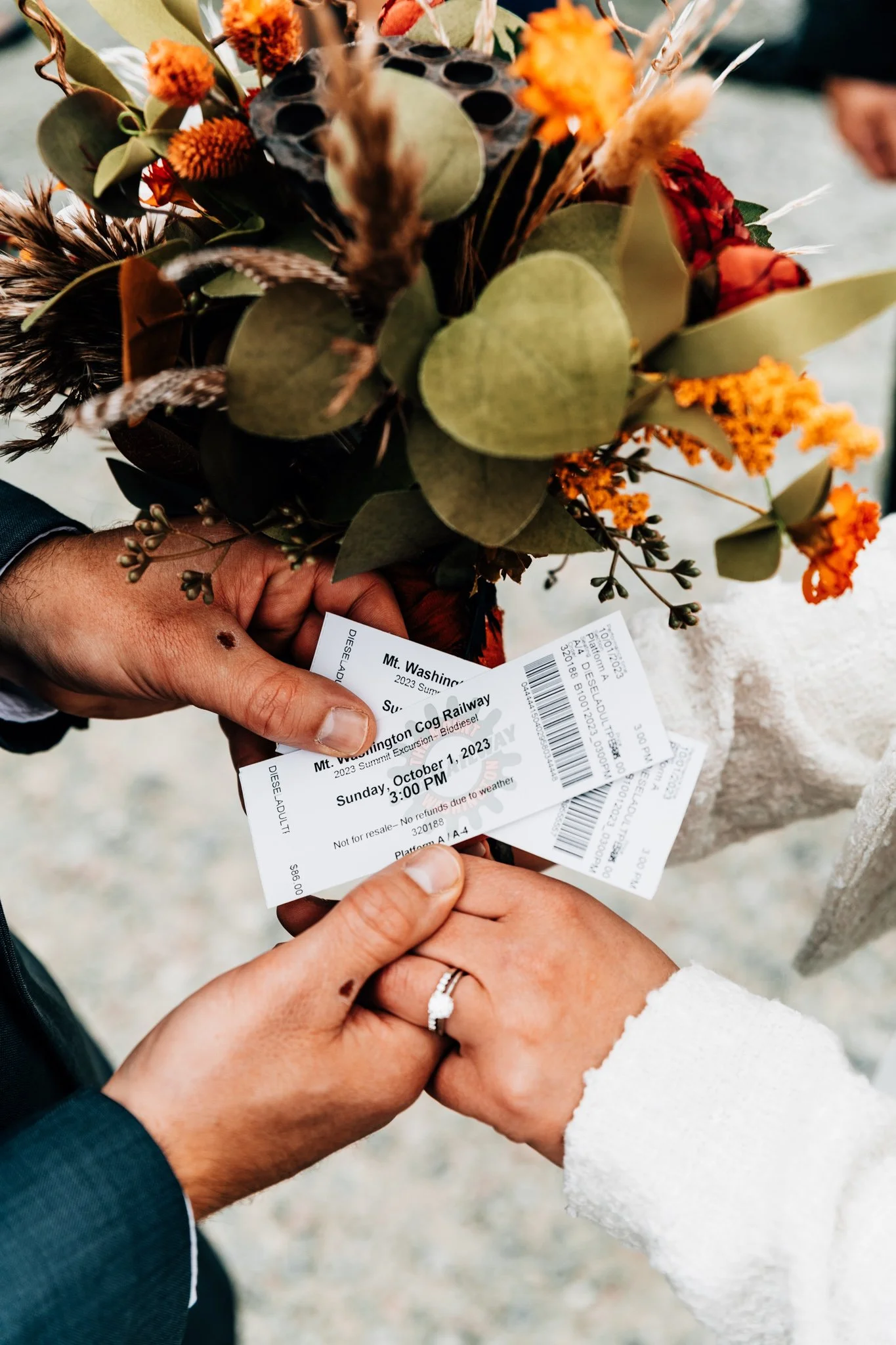 Hands holding Mount Washington Cog Railway tickets dated Sunday, October 1, 2023, in front of the bridal bouquet