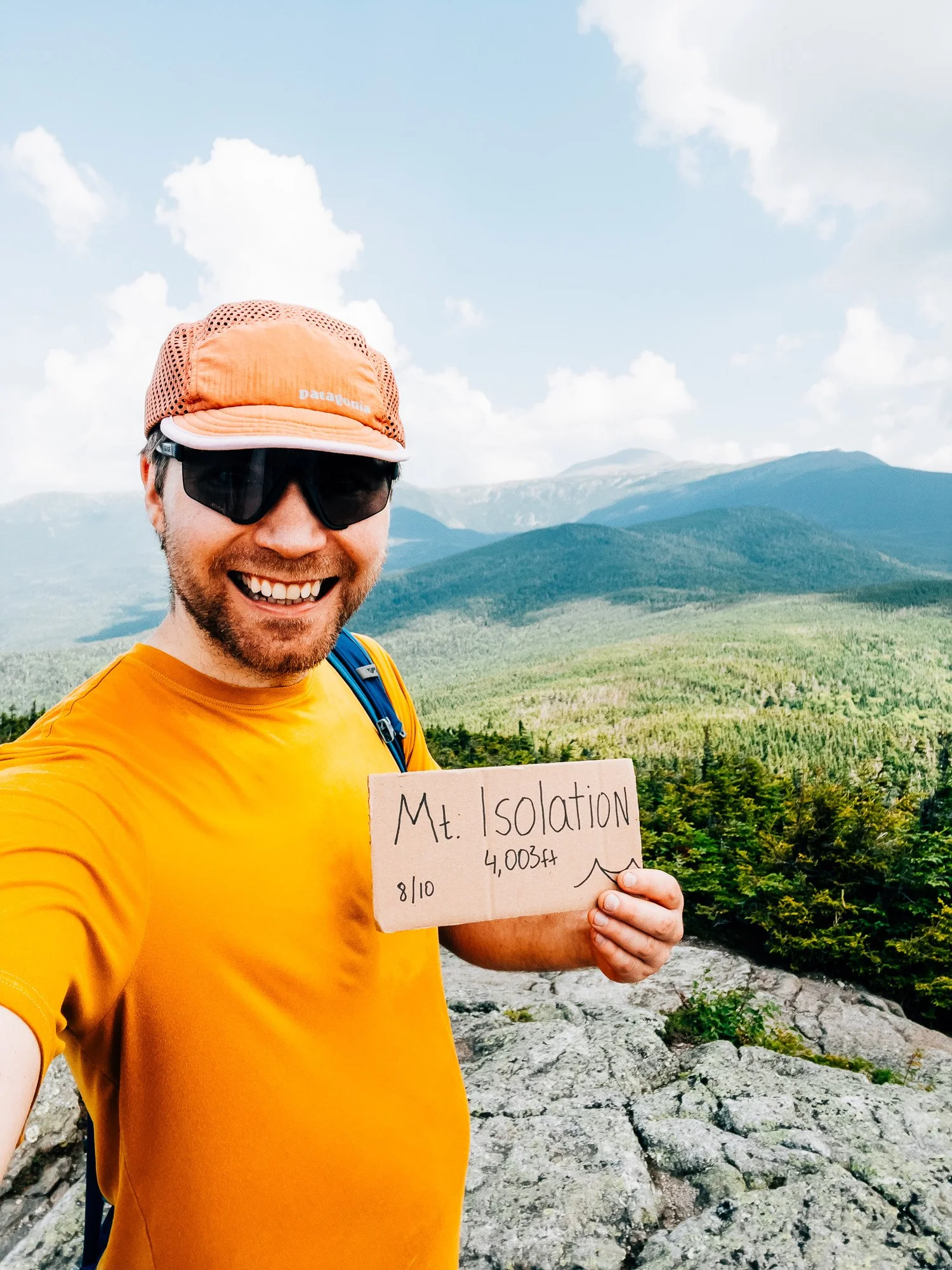 Holding a summit sign at Mount Isolation