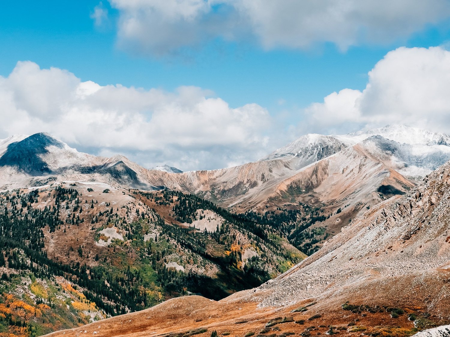 Early-fall alpine views: blue skies, snowy peaks, orange aspens, and yellow tundra