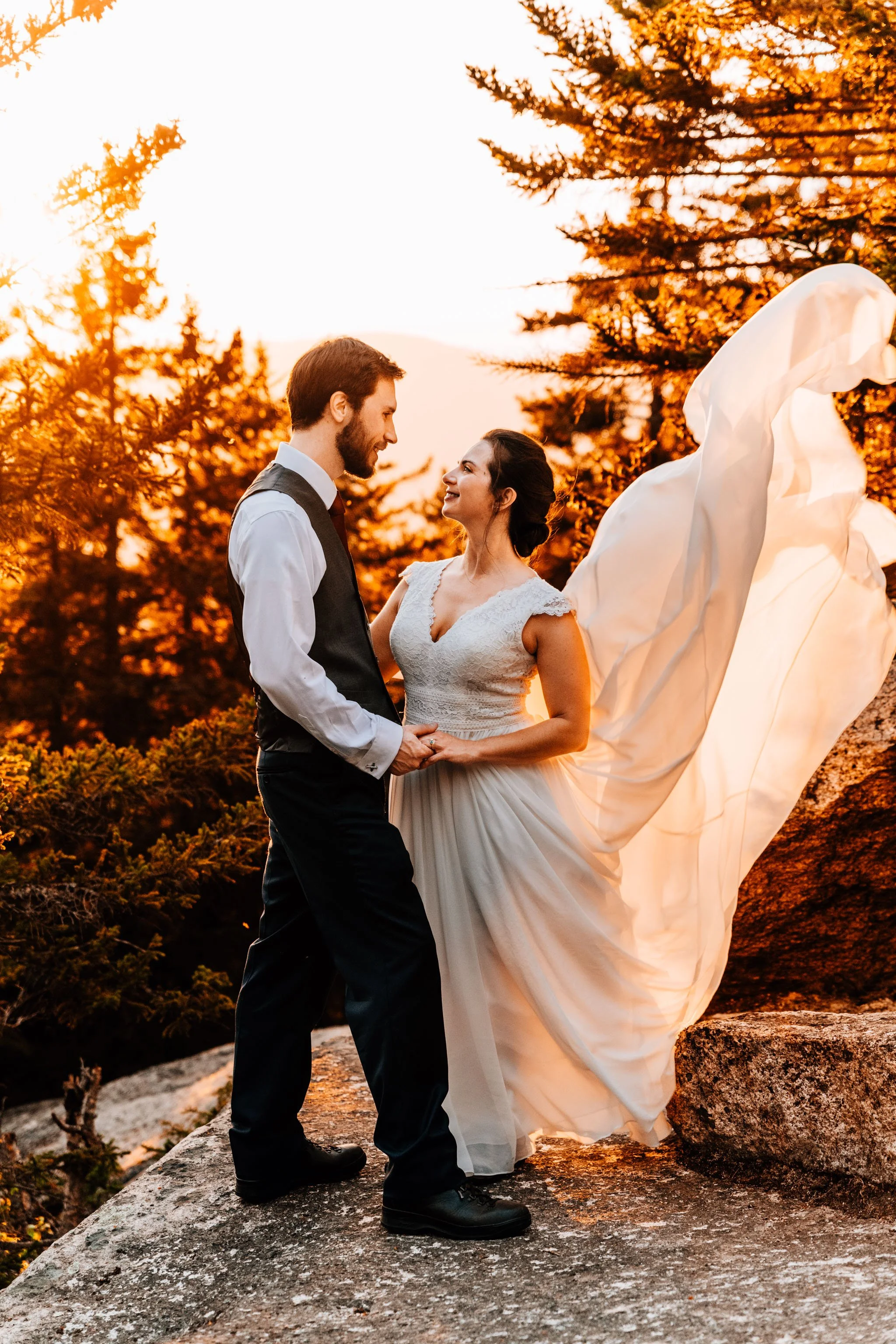New Hampshire bride's dress billowing in the wind at sunset during her adventure elopement