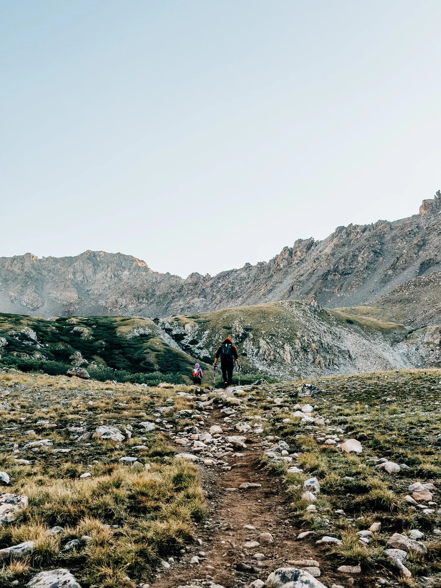Two hikers walking into the Horn Fork Basin meadows with Mount Harvard in the distance