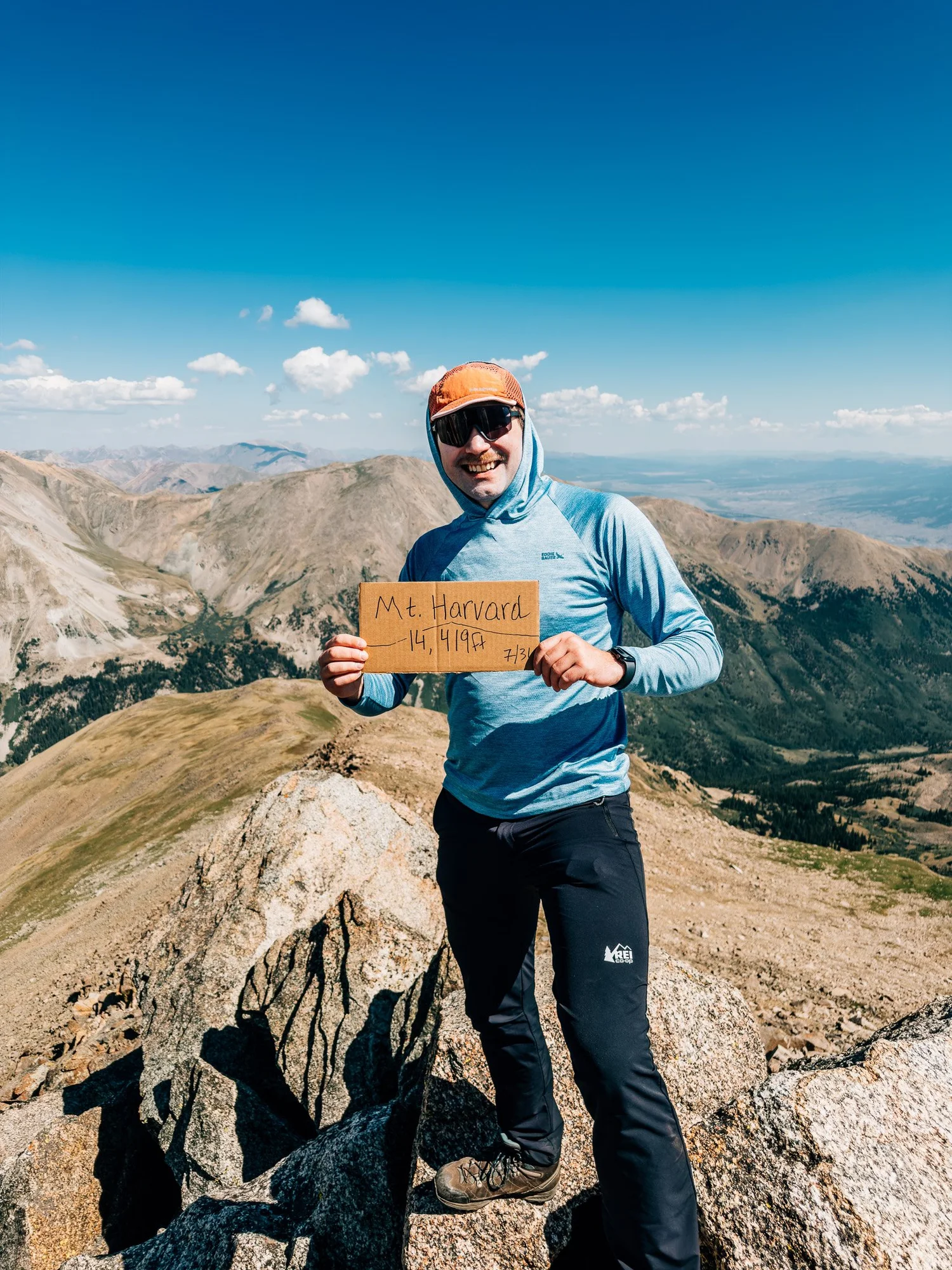 Anton on the Mount Harvard summit holding a cardboard summit sign