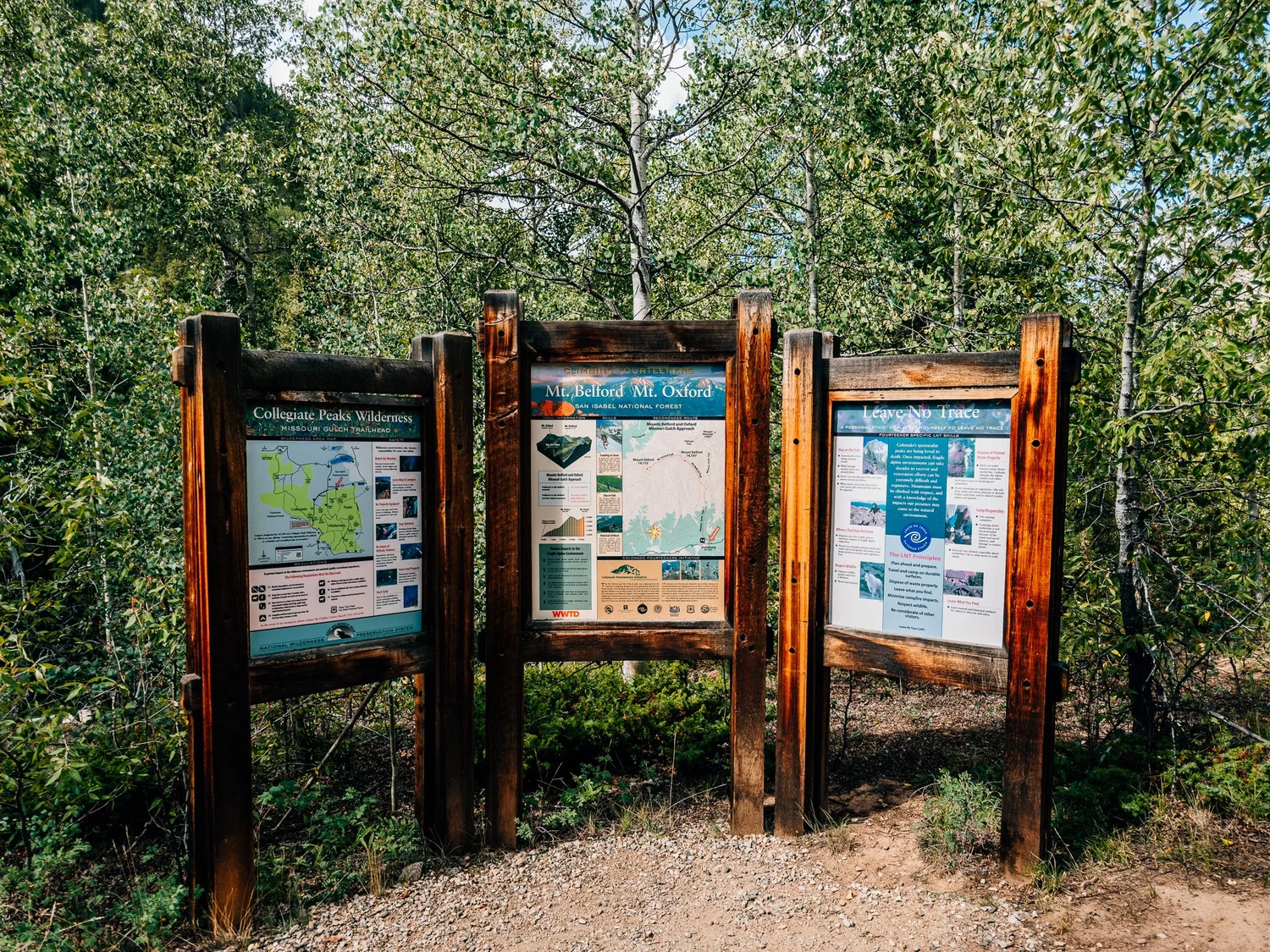 Three wooden trailhead boards at the Missouri Gulch Trailhead: a Collegiate Peaks Wilderness map, Mount Belford and Mount Oxford info, and Leave No Trace
