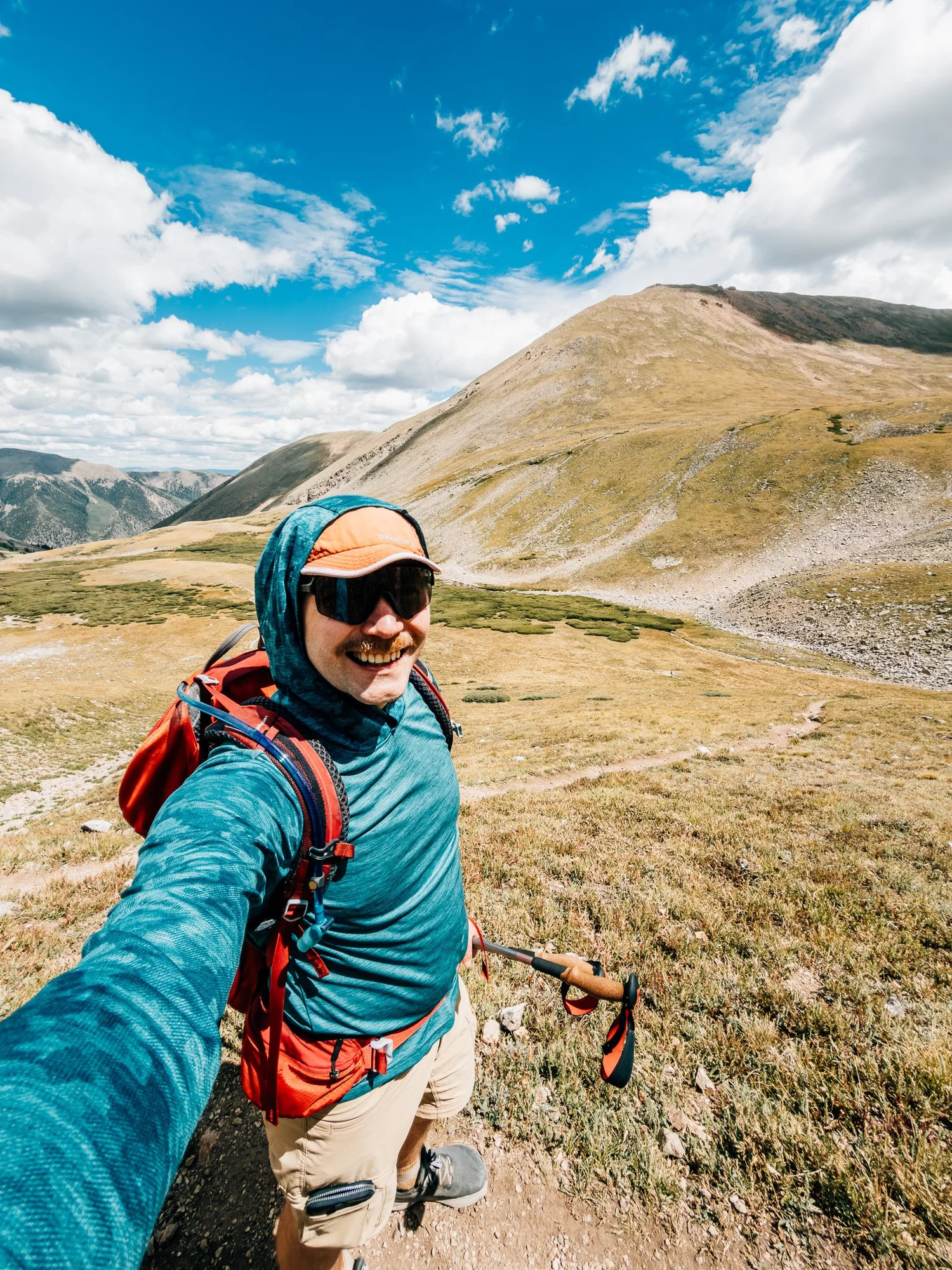 Anton in a hooded sun shirt and orange cap taking a selfie on the trail below Missouri Mountain