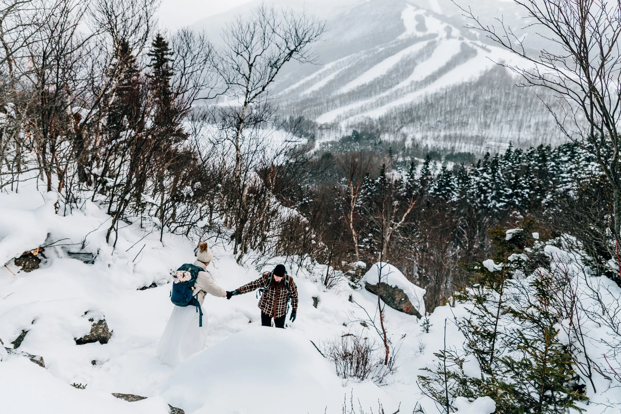 Couple during a winter adventure elopement in Franconia Notch with mountain views