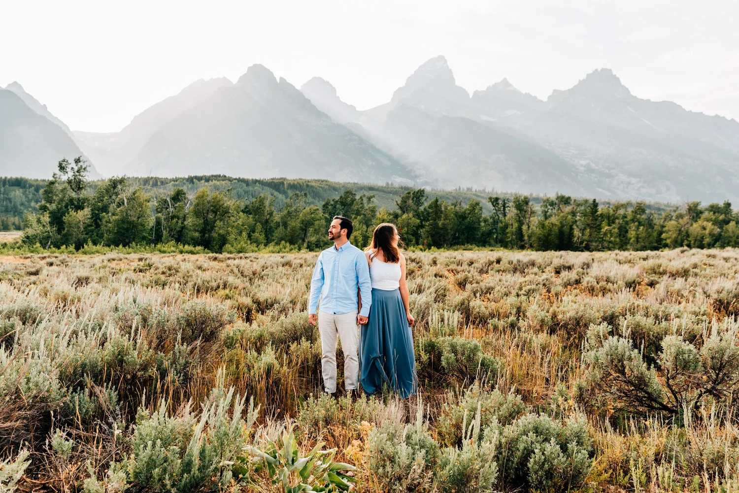 Couple running through wildflower meadows during their Grand Teton elopement