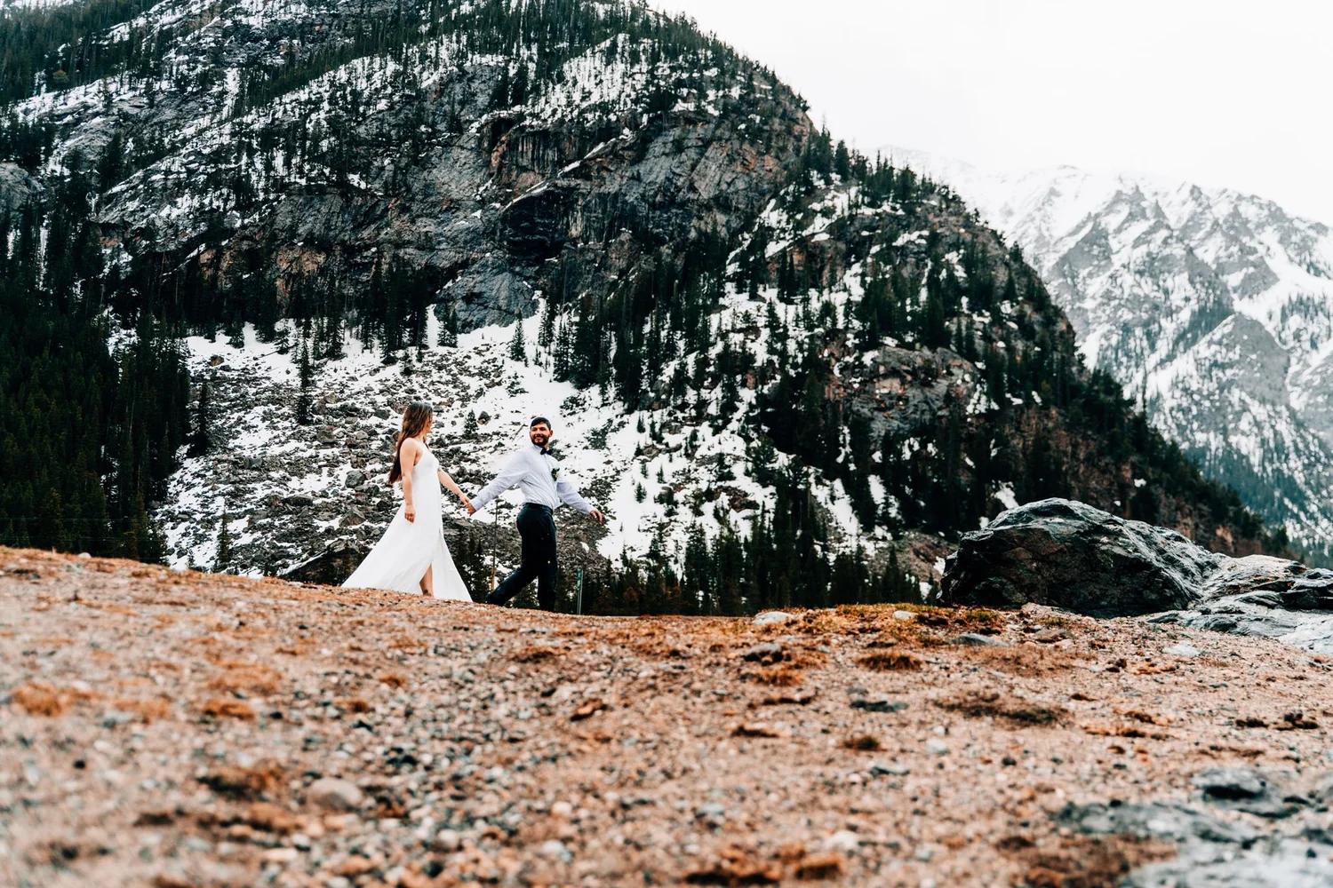 Couple walking hand in hand below snow-dusted peaks at Officer's Gulch, Colorado