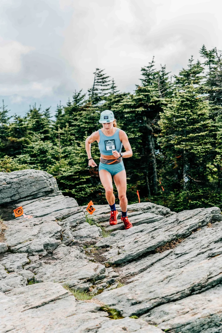 Cirque Series racer in bib 18 climbing granite slabs past course flags at Killington