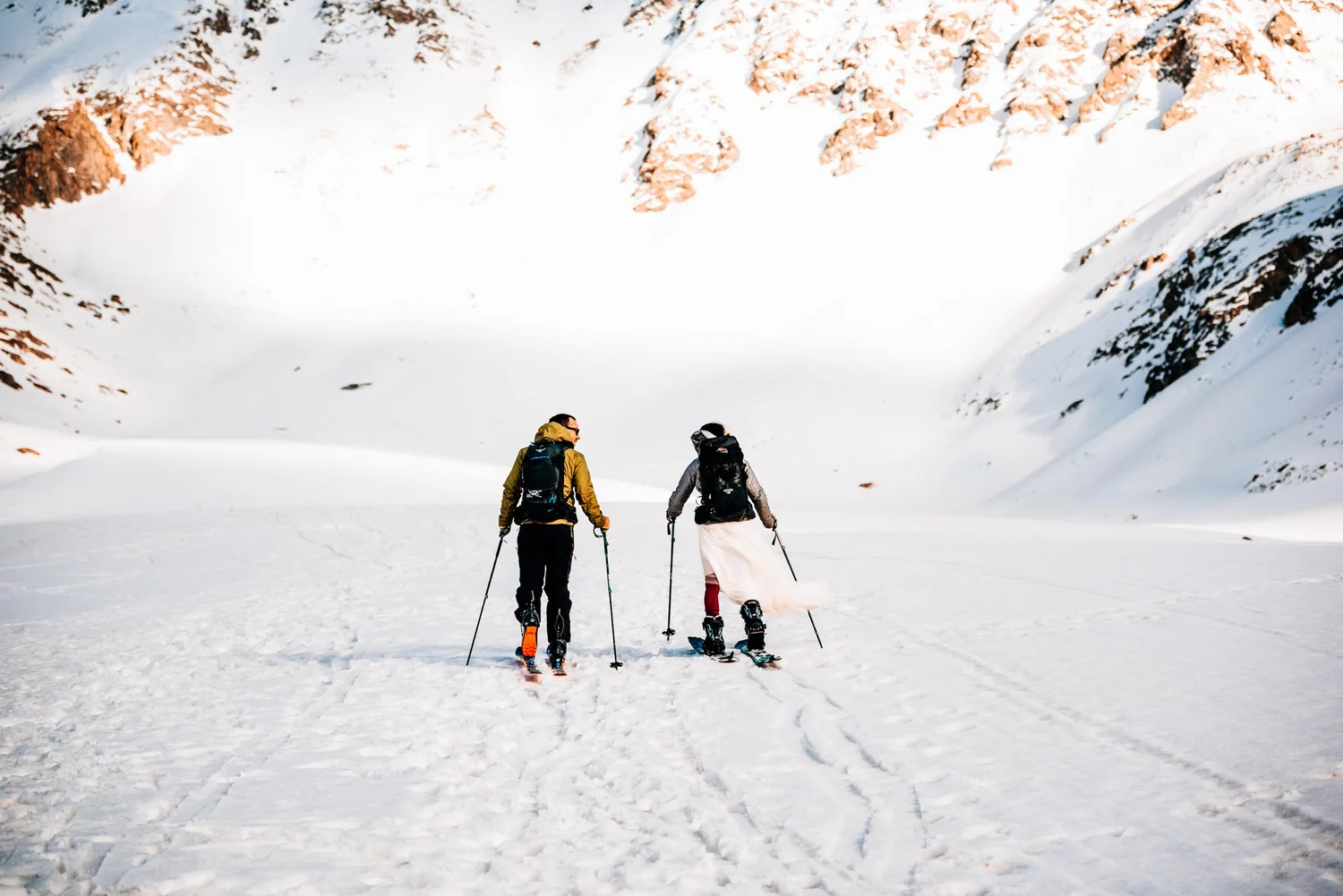 Couple ski touring uphill in a snowy Colorado basin on their elopement day