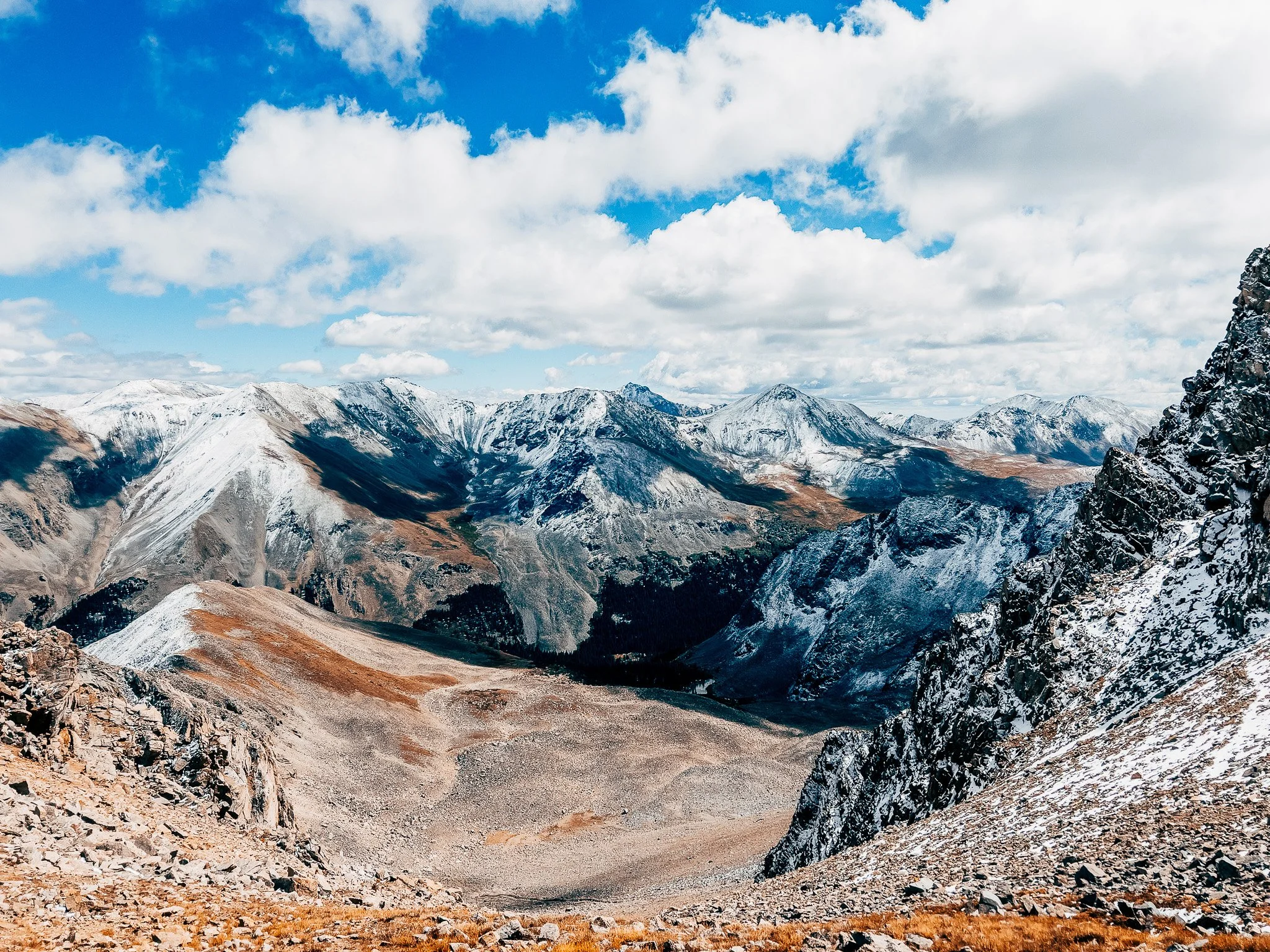 Snow-dusted peaks and an alpine basin under towering clouds near Huron Peak