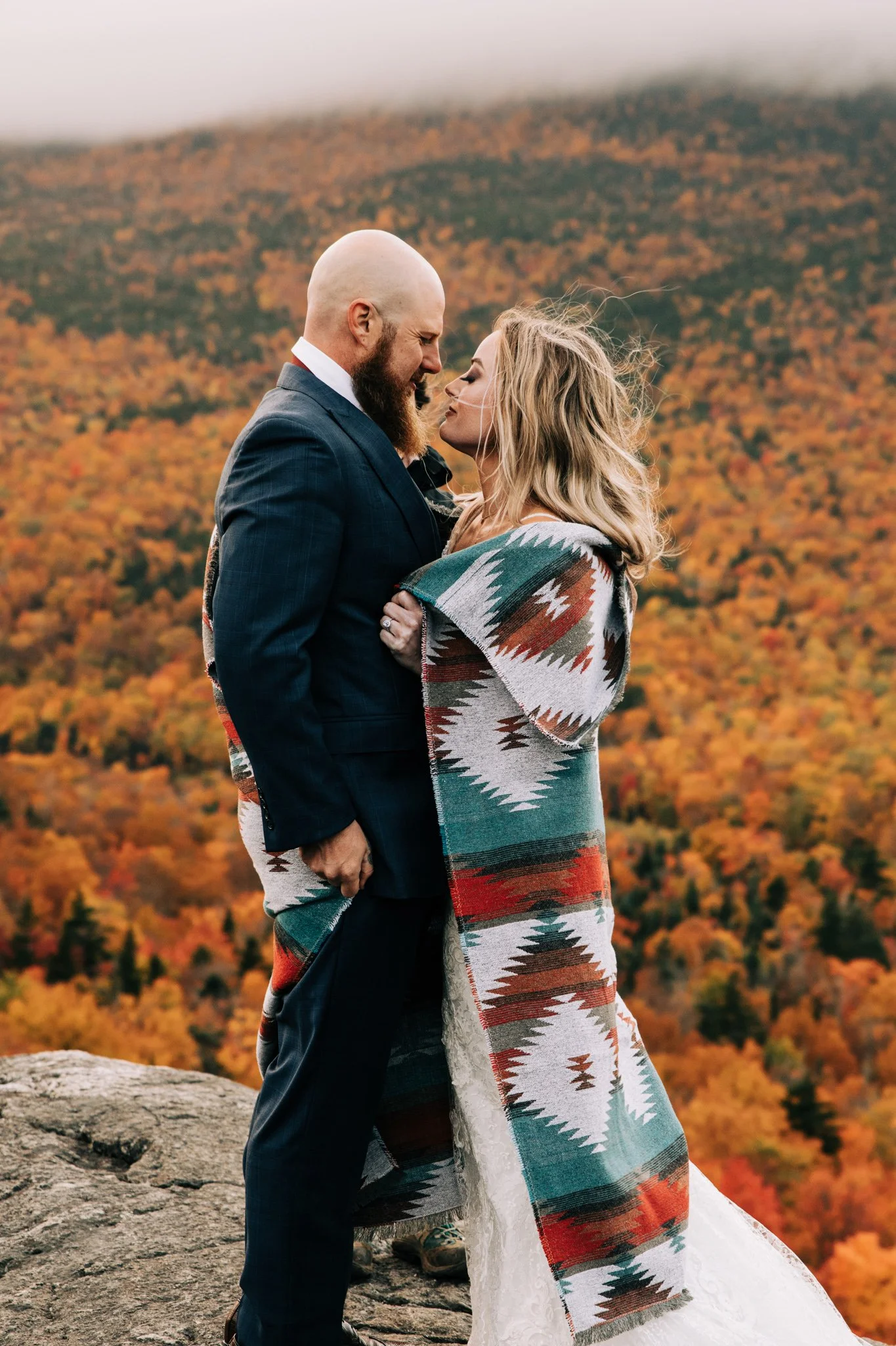 Couple in layered textured clothing surrounded by peak fall foliage at Pinkham Notch in the White Mountains
