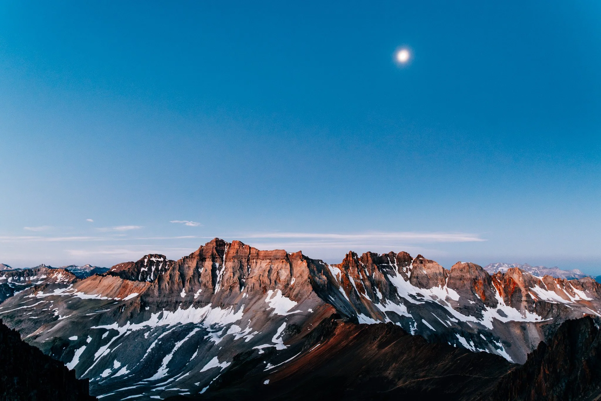Snow-streaked red-rock ridgeline of the San Juan Mountains under a clear sky near Mount Sneffels
