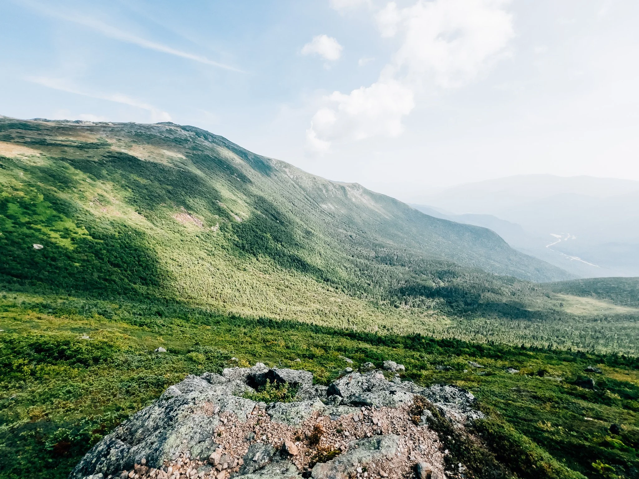 Green Presidential Range slopes and a granite outcrop above a wide valley, from Mount Isolation
