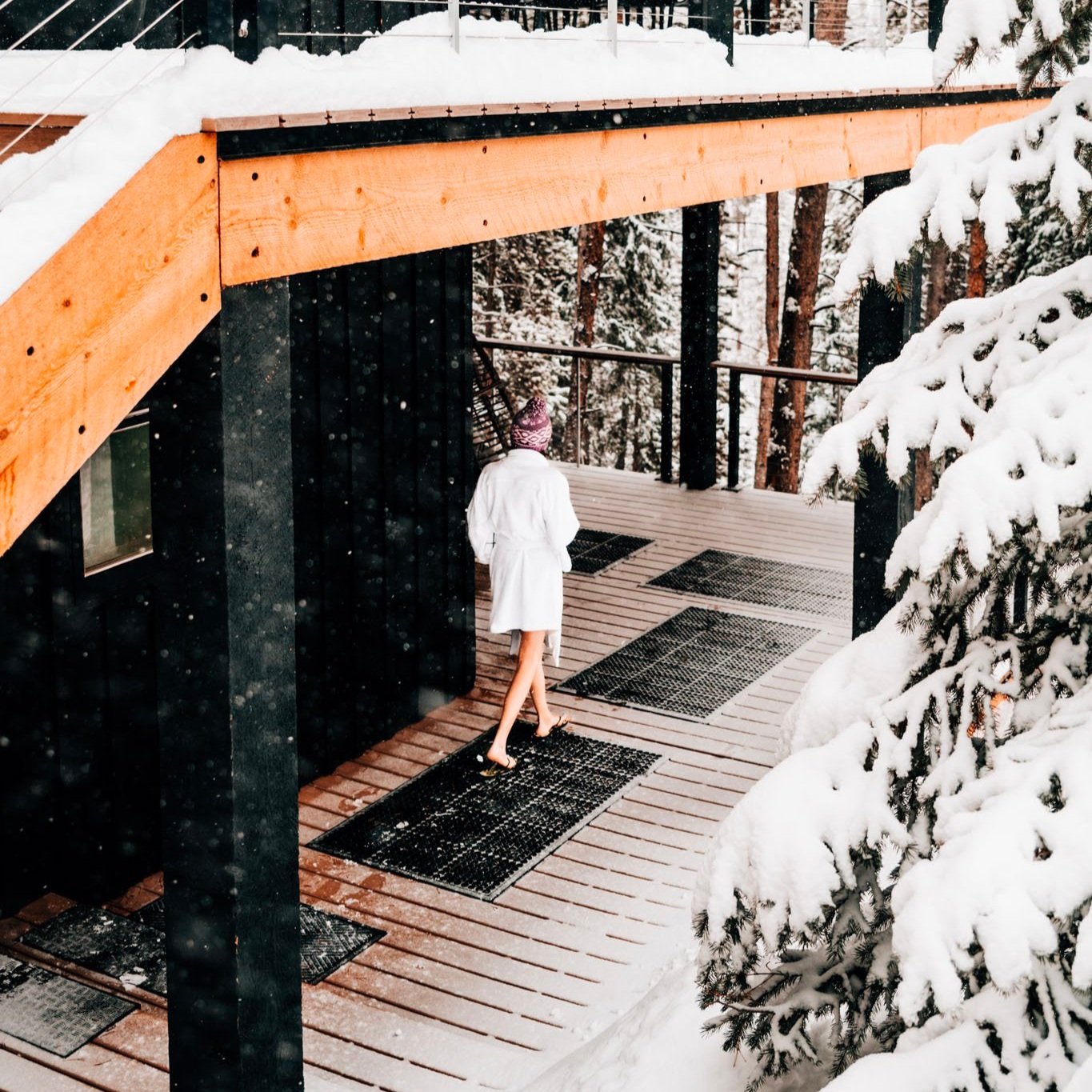 Snowy cabin with person in white robe on deck