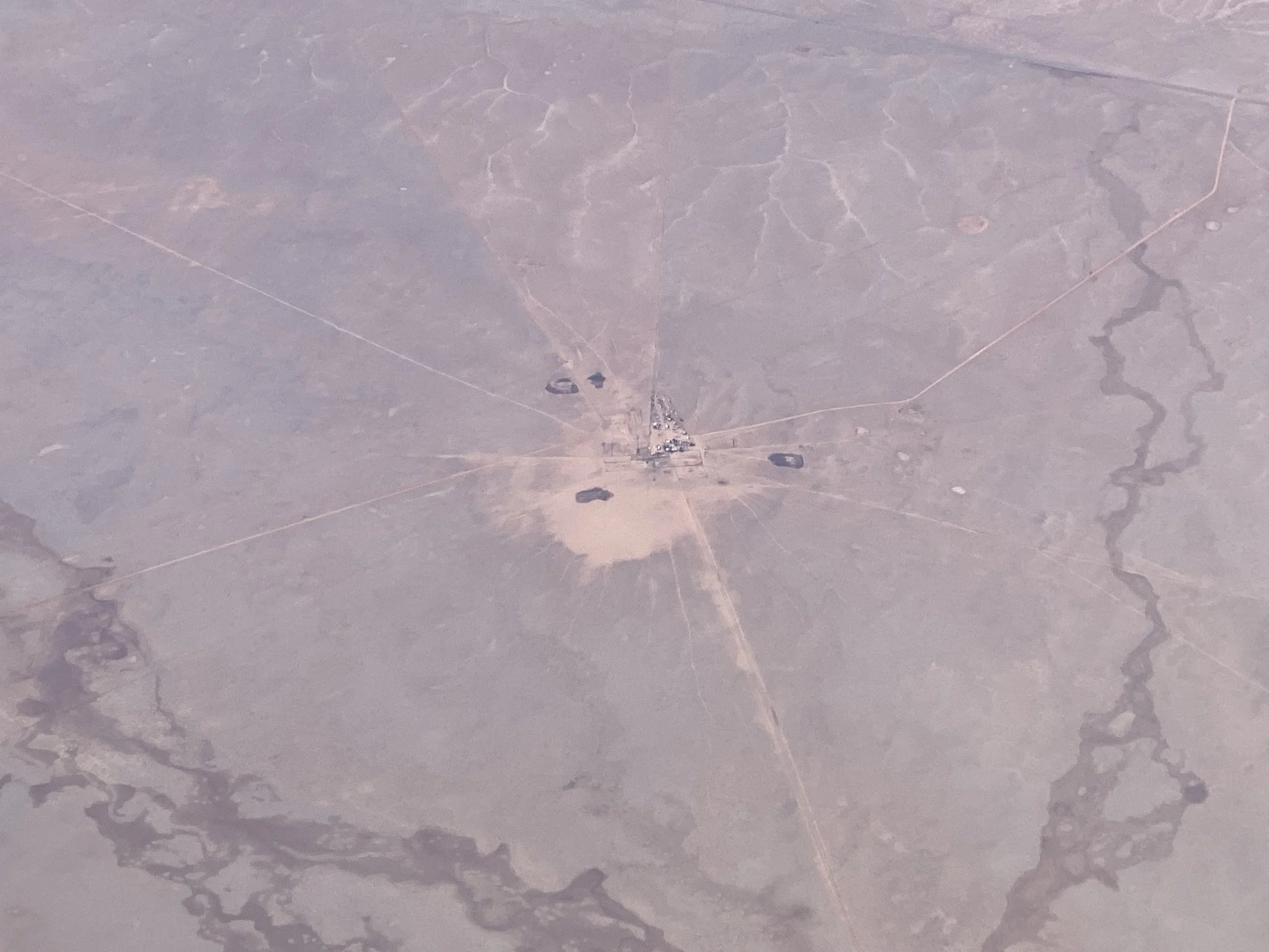 Aerial view of a small desert base or facility with dirt roads connecting structures and several water bodies.