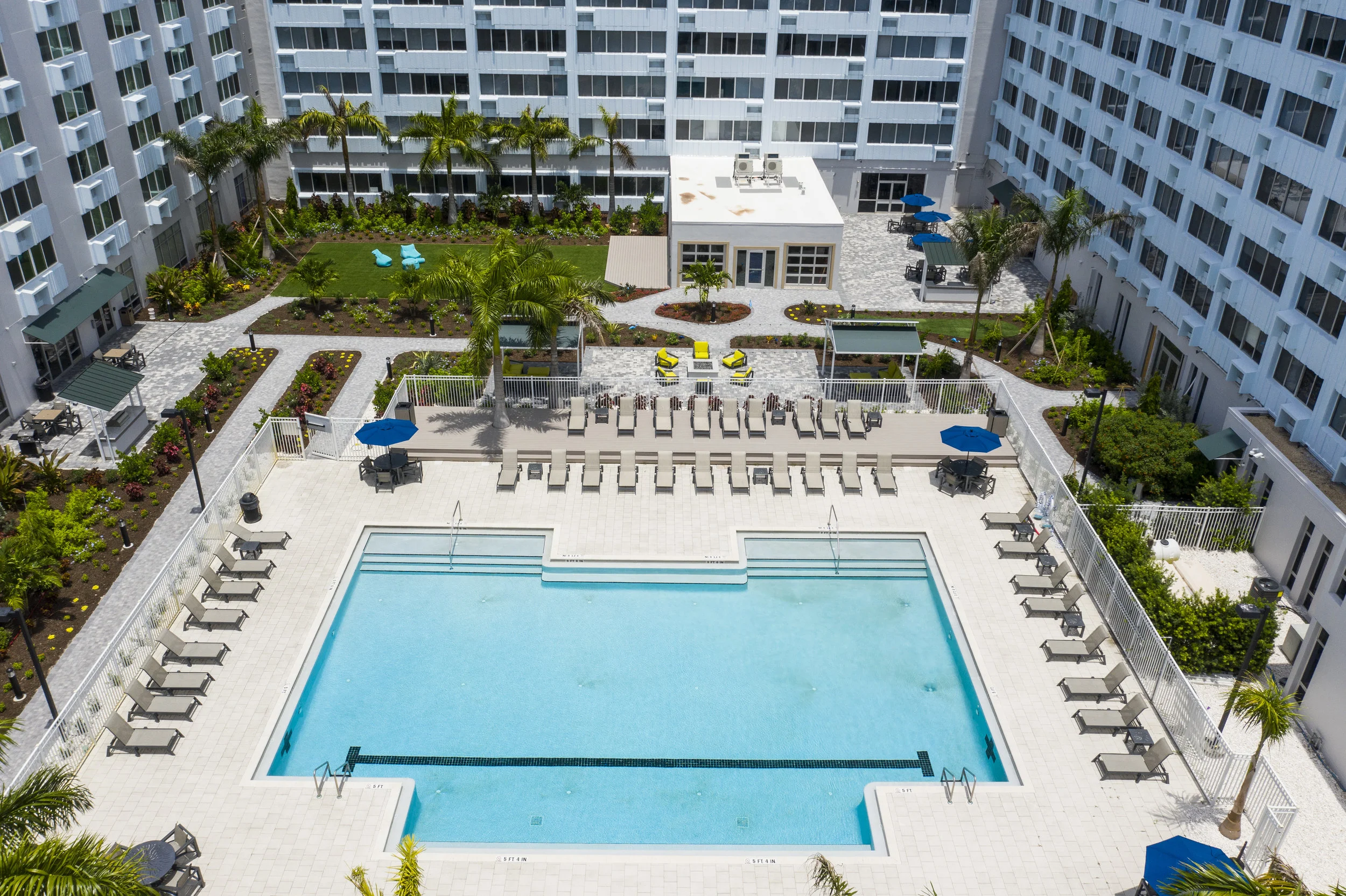 The resort-style pool area features a new deck, a turf lawn, and lounging areas.