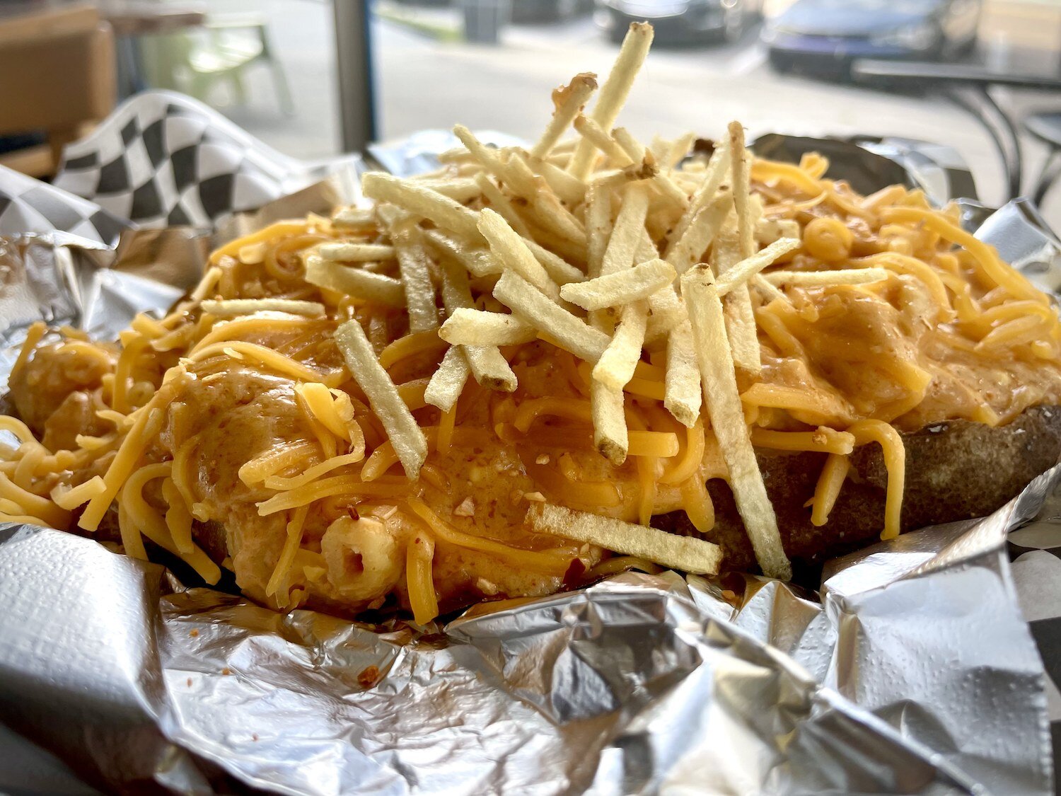 The Mac n Cheese Potato topped with home-made mac n cheese, a house cheese sauce, shredded cheddar, and potato sticks