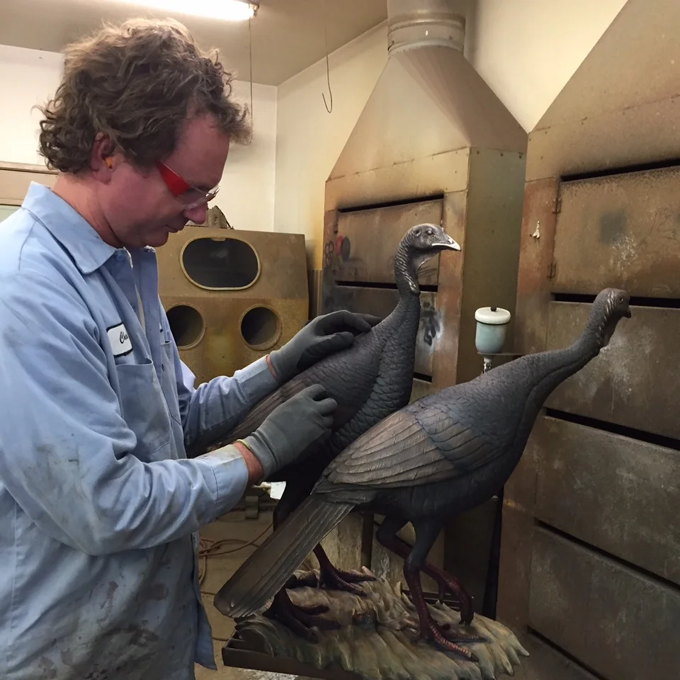 Patina artist Chad Quam working on hen sculptures.