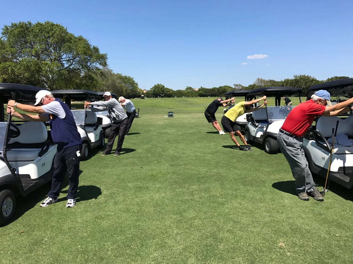 MEMBERS AT A LOCAL COUNTRY CLUB DEMONSTRATING GOLF STRETCHES FROM THEIR GOLF CARTS