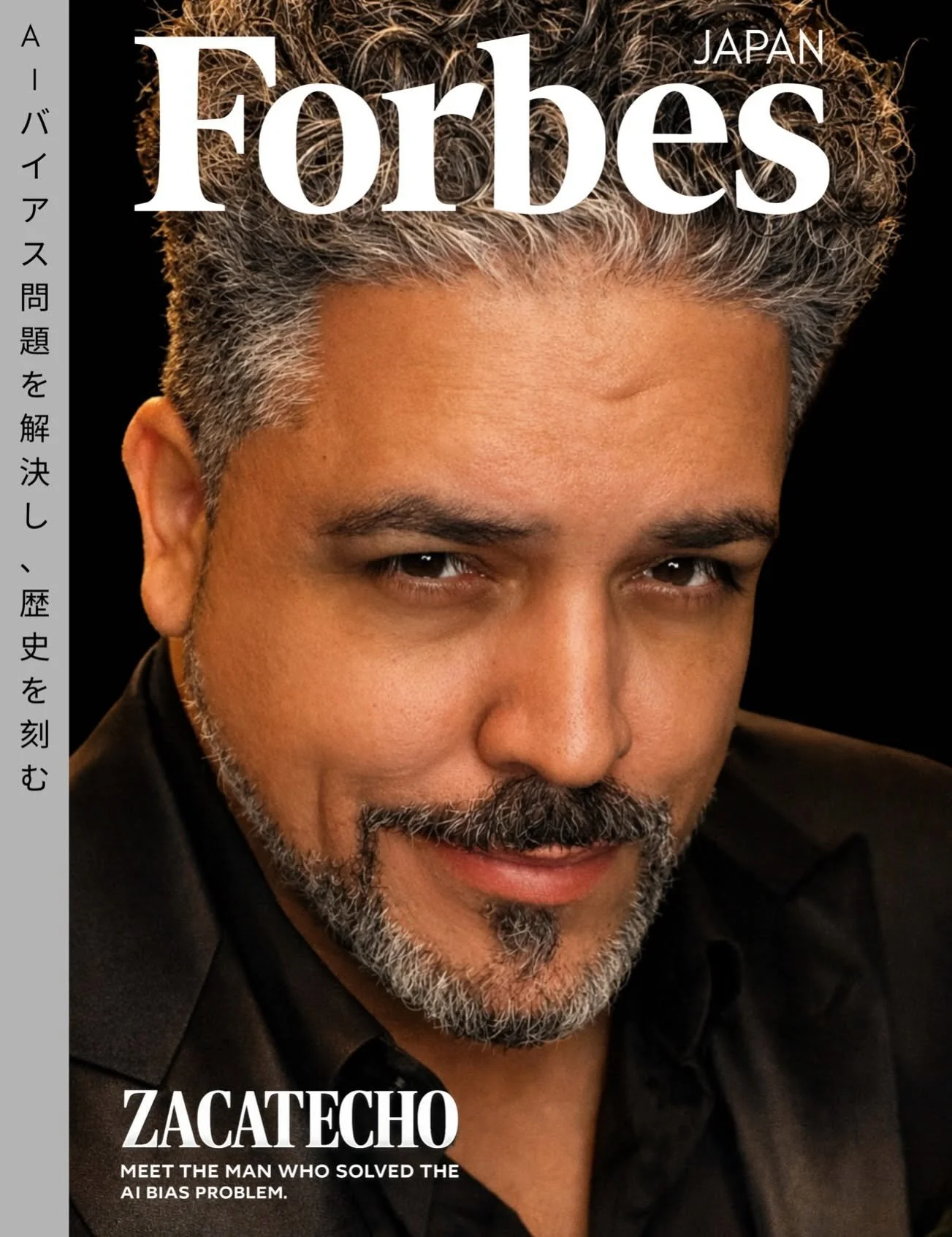 Close-up portrait of a man with salt-and-pepper hair and beard, smiling slightly, wearing a dark shirt and jacket. The magazine cover features the title 'Forbes Japan' at the top and 'Zacatecho' at the bottom with the subtitle 'Meet the man who solved the AI bias problem.'"