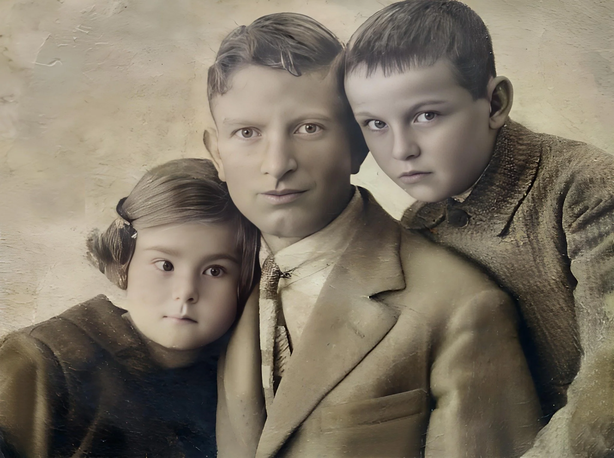 A man with two children, a girl and a boy, all with serious expressions, dressed in vintage clothing, posed closely together against a textured background.