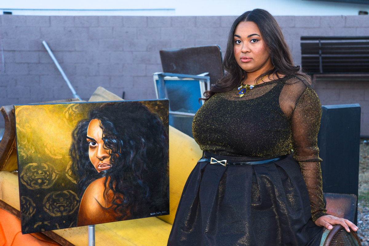 Artist Antoinette Cauley pictured with her painting titled "Love Can Make A Bitch Go Crazy". Photo by Dontae Tubbs/ Hair by Annie Cavnaugh/ Makeup by Stephanie Hernandez