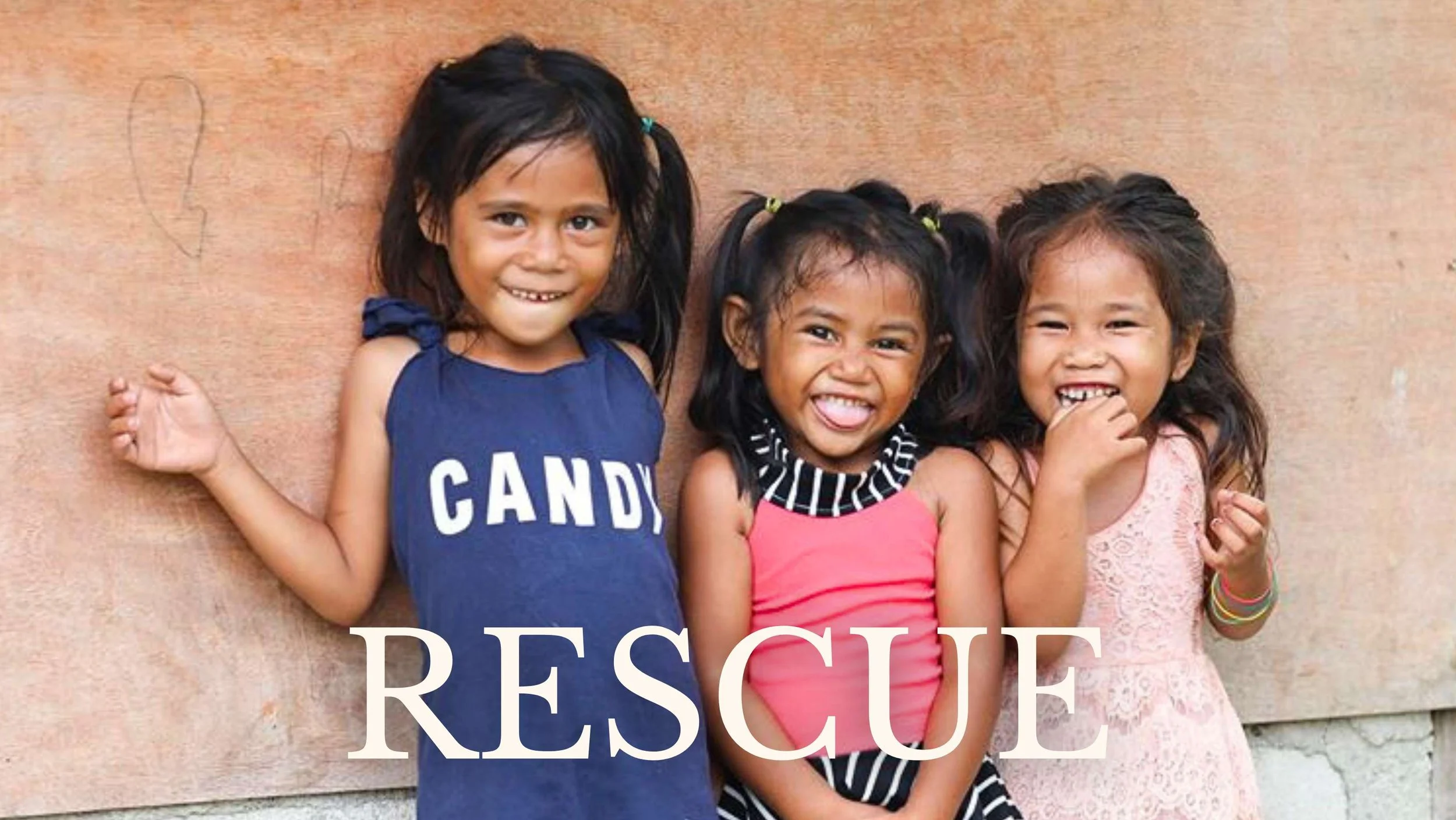 three young girls in third-world country lean against wall and smile at the camera, rescue human trafficking project