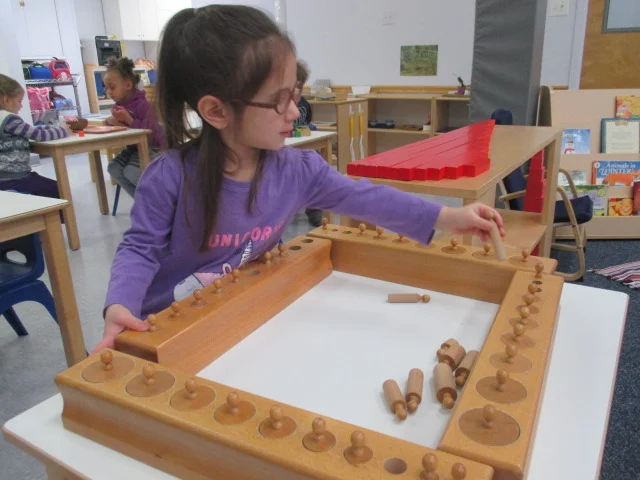 What does a Primary 1 student do when she has
mastered the Knobbed Cylinders? She
brings all the four blocks of Knobbed Cylinders out, empties them and tries to
fit them all together at once. This is
her own interesting extension of the Knobbed Cylinders material.