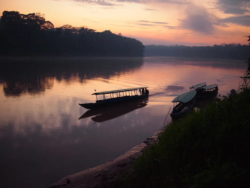 Boat navigating the Tambopata river during sunrise in the Peruvian jungle
