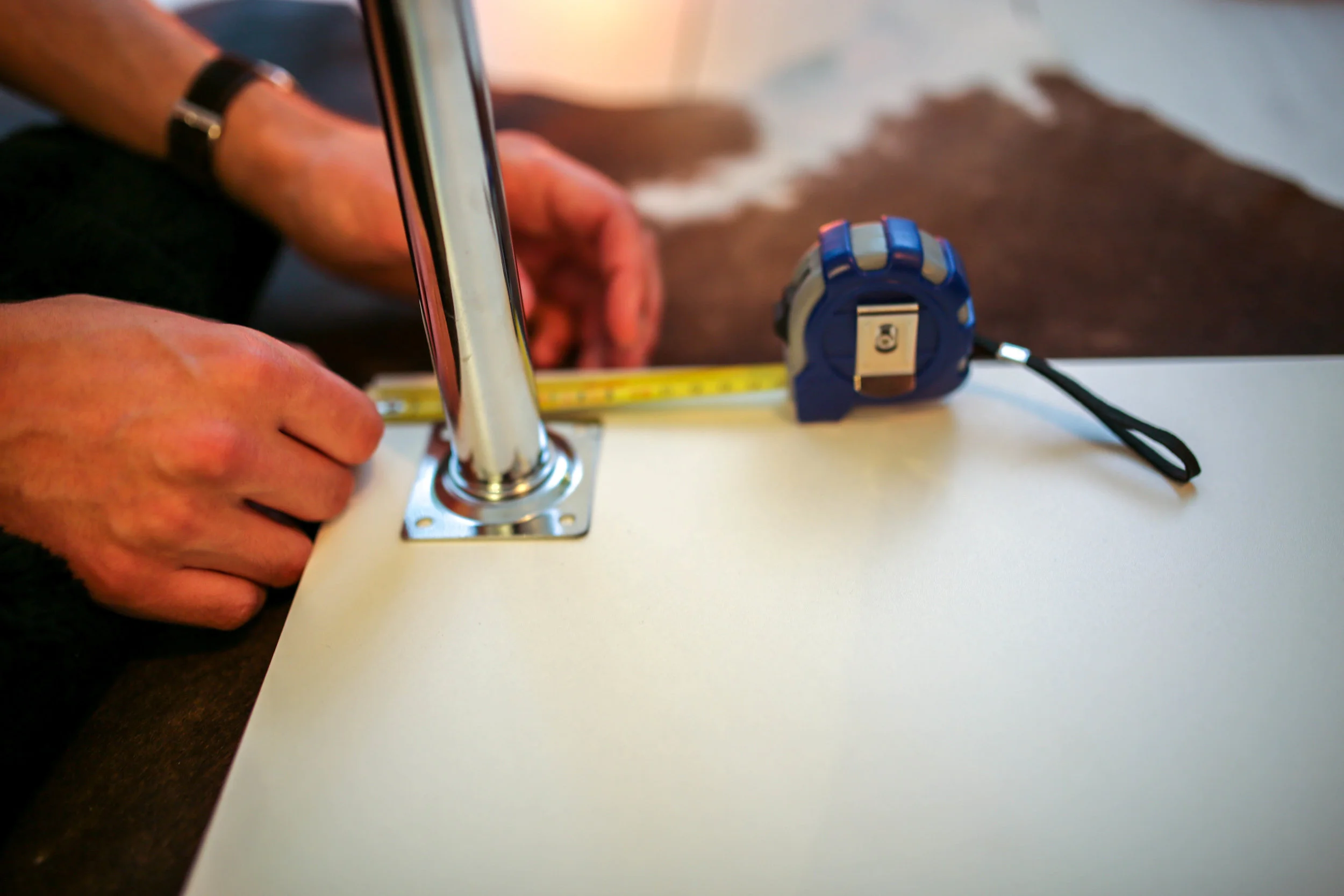 Measure the distance of the legs from the edges with the tape measure for where to drill holes and mark with a pencil. Make sure there is enough space for the floor trim to fit so that the desk top is flush with the wall