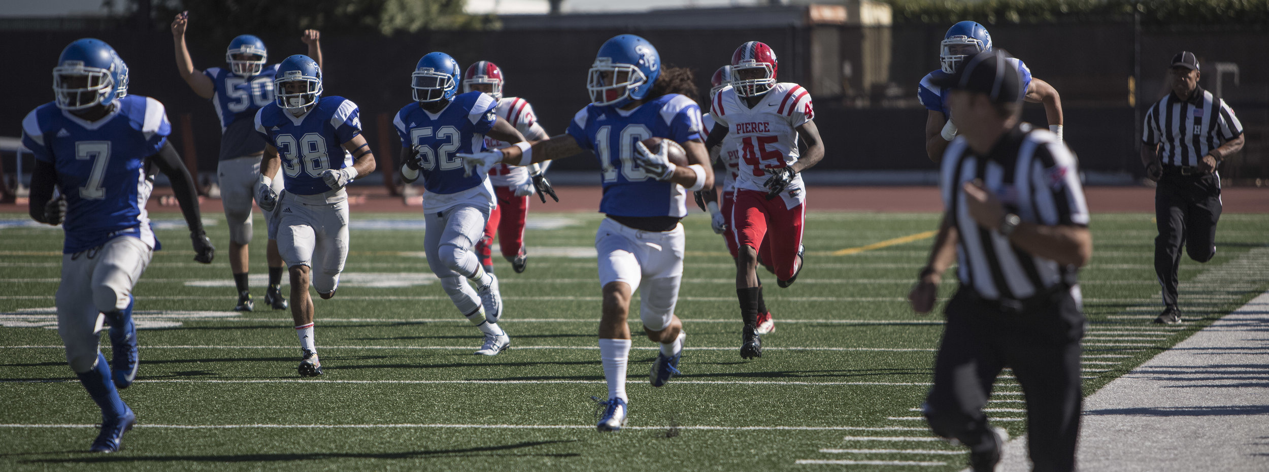  The Santa Monica College Corsair men's football team sophmore defensive back #10 Max Lyons (center,blue) runs the opening kickoff return in for a hundred yard touchdown against The Los Angeles Pierce College Brahma Bulls for the final game of the re