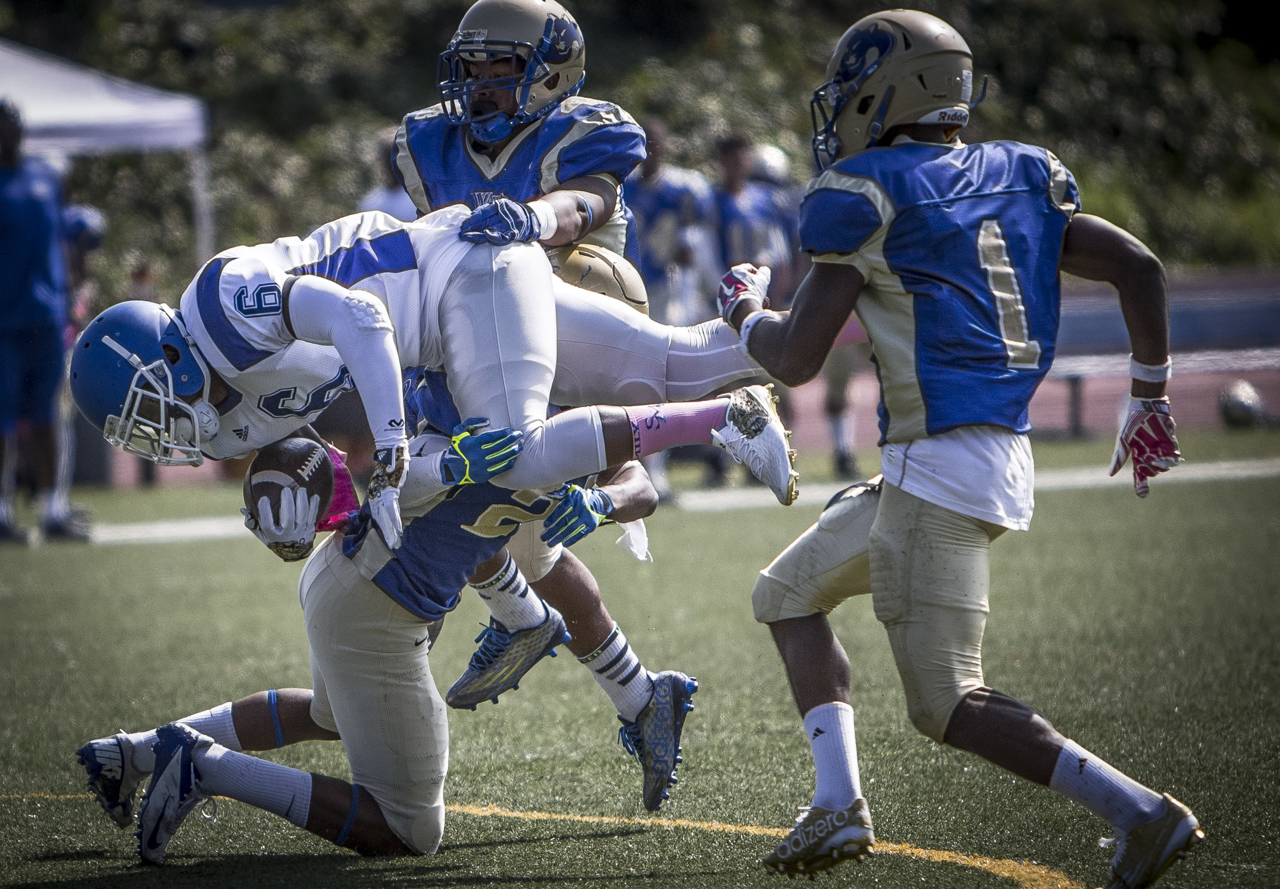  The Santa Monica College Corsairs men's football team sophmore runningback #6 Martaveous Holiday (white,middle) gets tackled after making a rush for a long gain aganst The West La College Wildcats sophmore defensive back #2 Grant Cohen (blue,bottom)