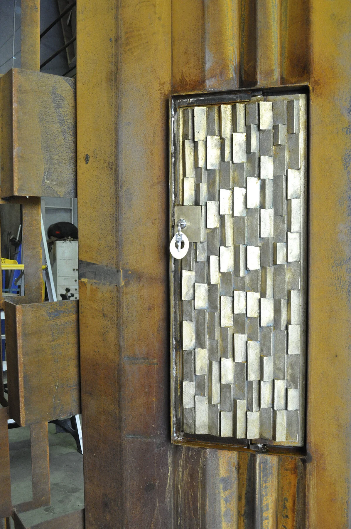  Set within the weathering steel gate is a cast brass access hatch to the locking mechanism behind 