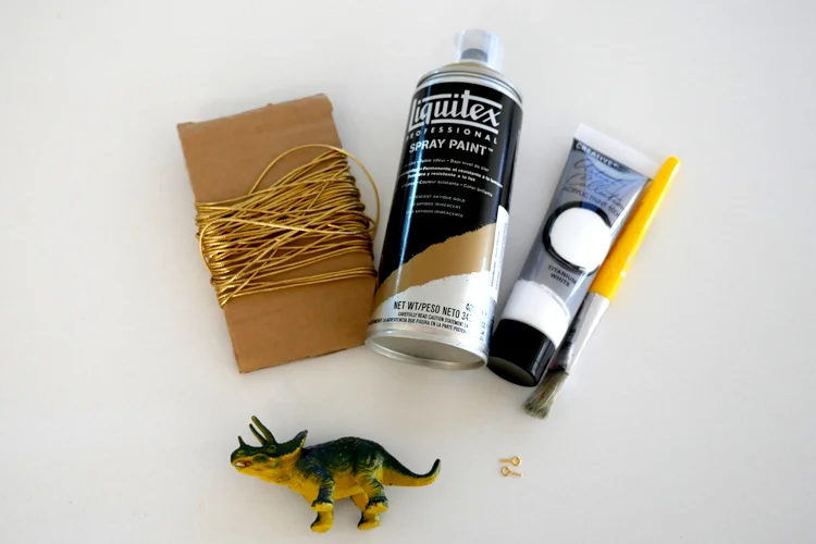 The materials we used: cheap plastic dinosaurs, small screw hooks, white paint, gold spray paint and gold string.