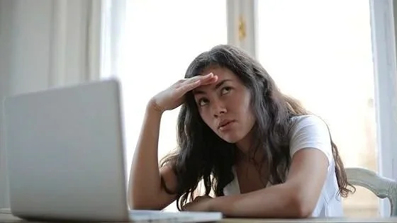 woman at computer looking thoughtful indicating AI can be used as a tool for introspection.