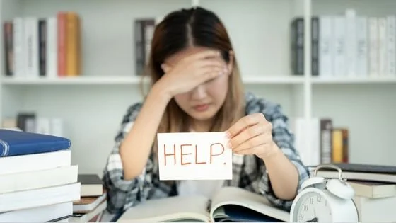 a woman holding a sign that says help indicating asking for it even if you aren't at some arbitrary distress level you've set or compared against.