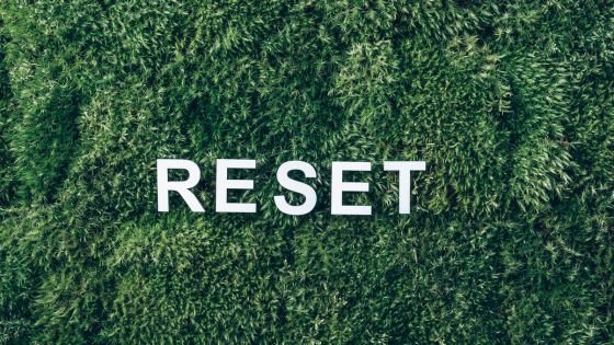 White word "reset" on top of grass to indicate sustainable growth and offering opportunities to frame slip-ups as momentary rather than nullifying progress.