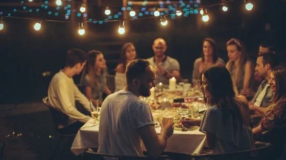 depicts couple in large gathering of friends indicating fit with established connections.