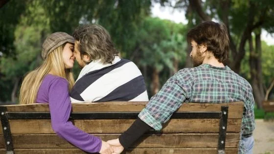 woman kissing a man and holding another man's hand behind his back. This could be consensual, but needs to be openly discussed.